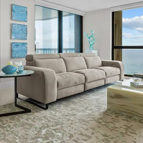 Beige sofa in a contemporary living room with large windows overlooking the ocean, featuring elegant.