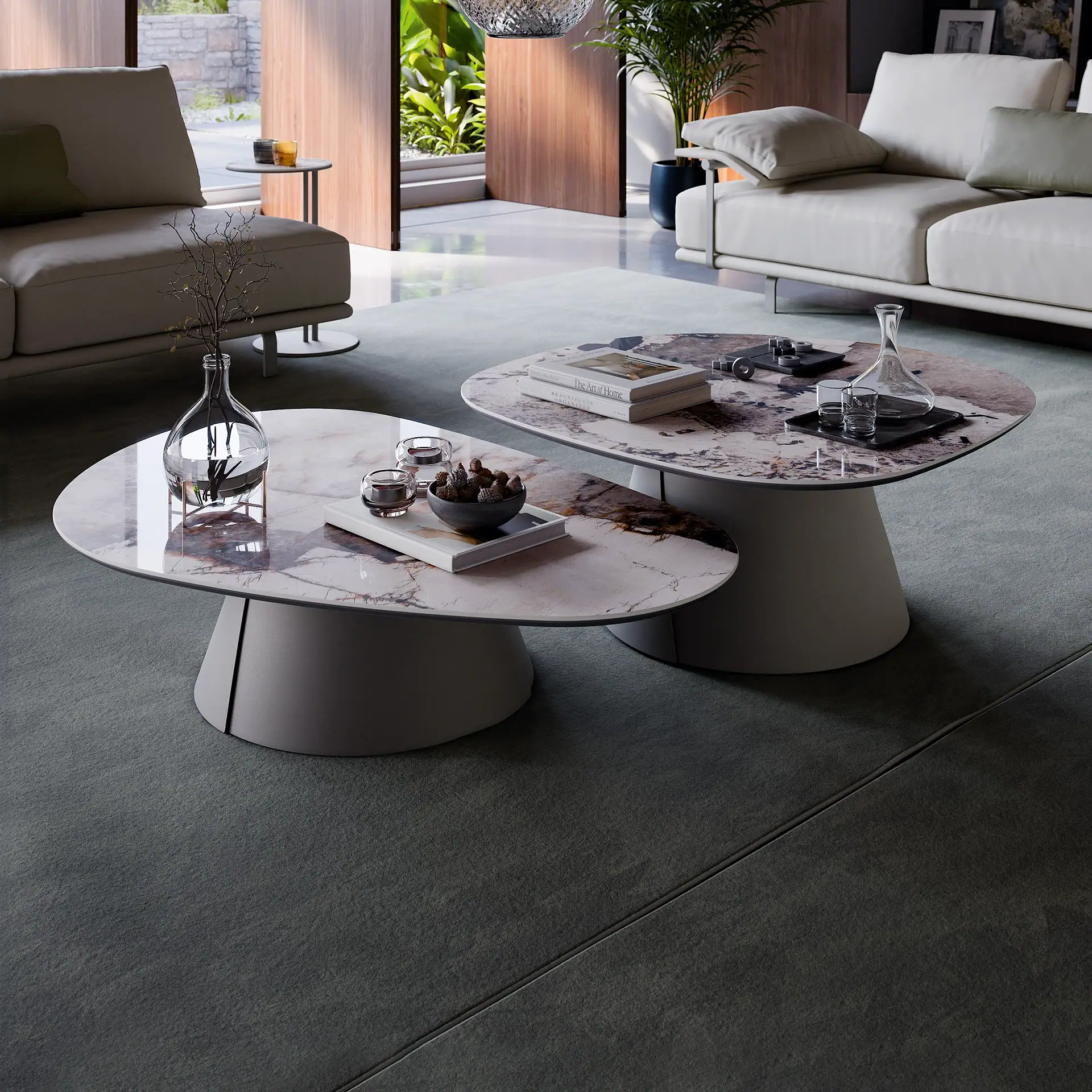 A modern living room with two oval marble coffee tables, light-colored sofas, and a view to a lush outdoor garden.