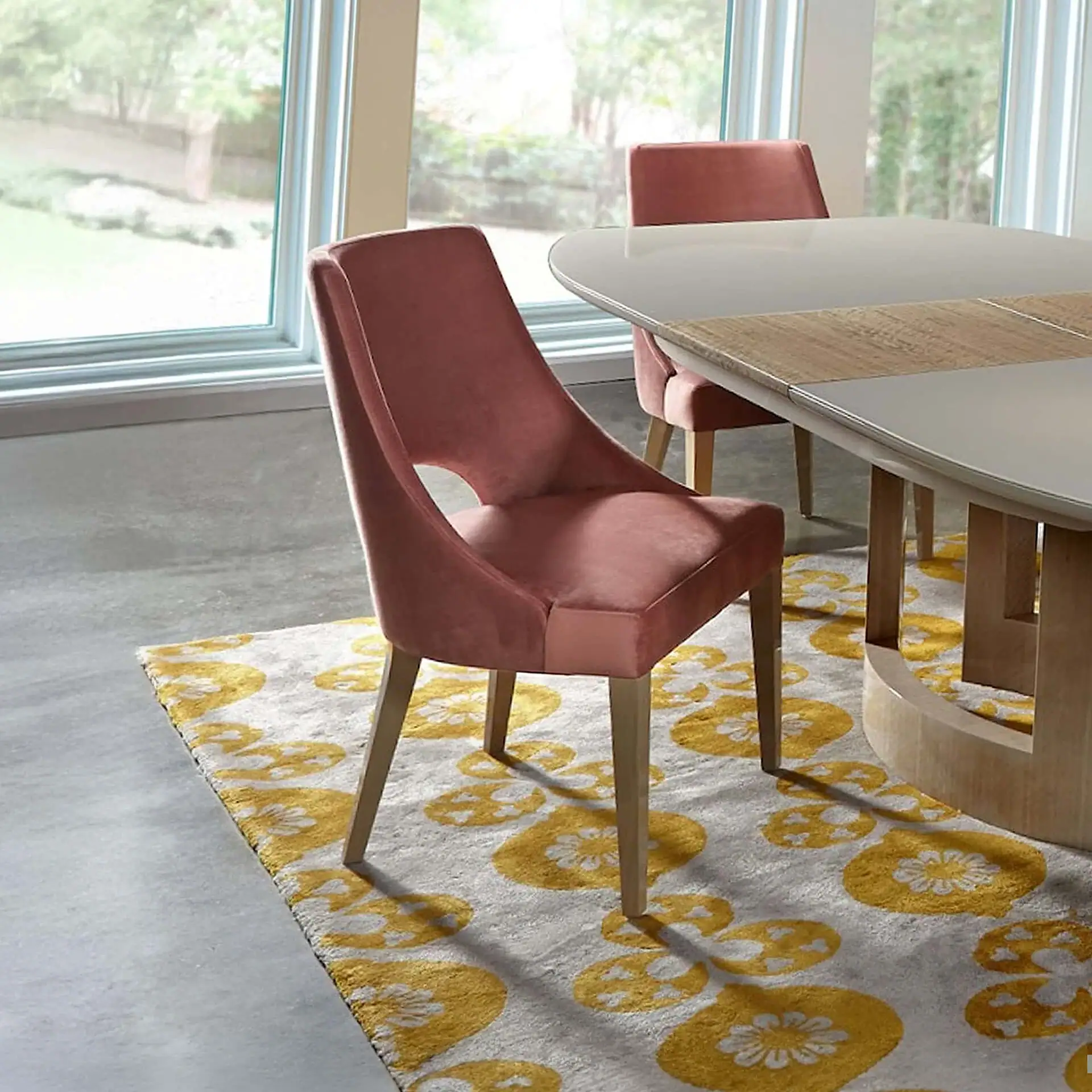 Stylish pink upholstered dining chair with wooden legs in a bright dining room.