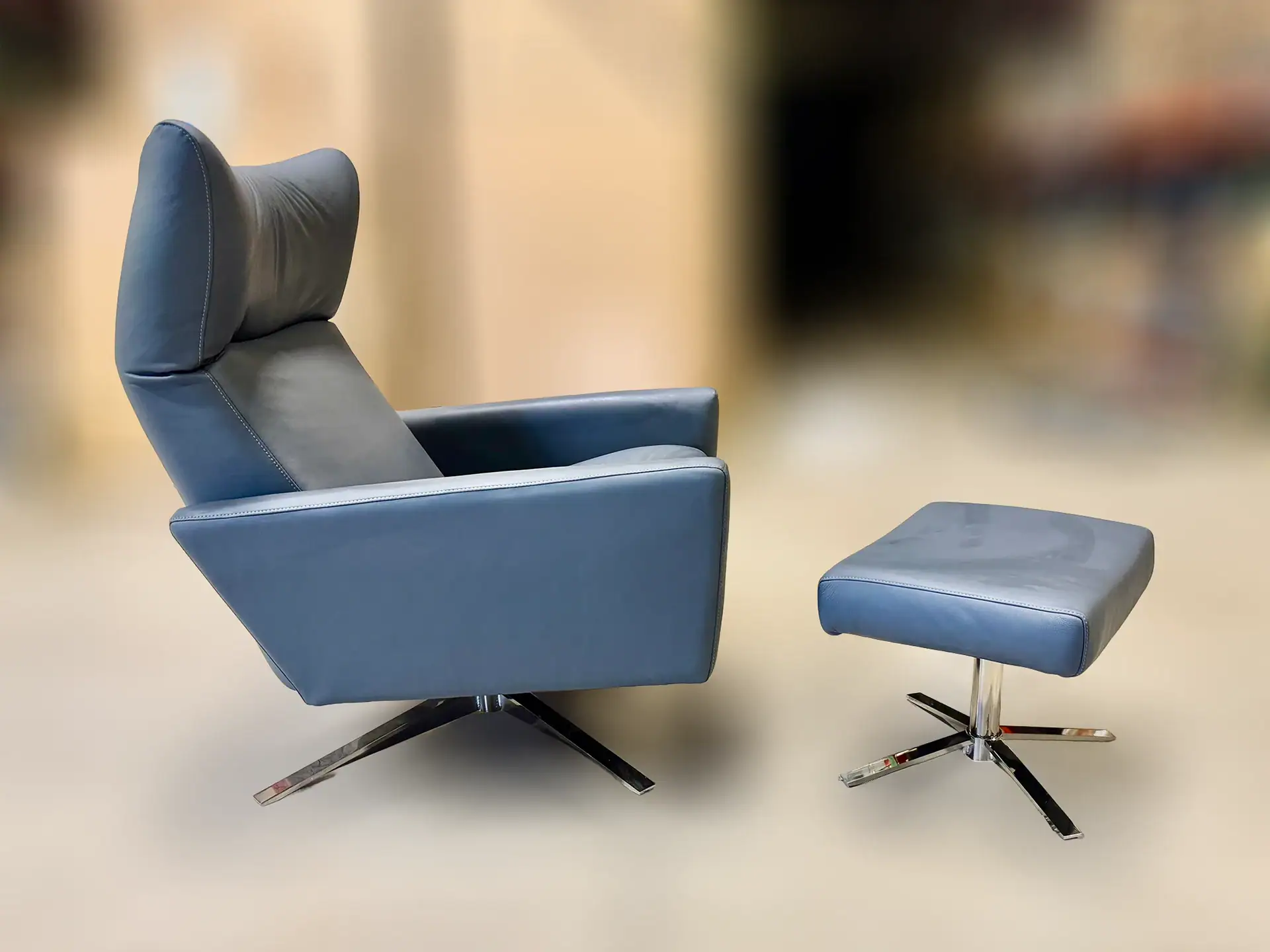 Modern blue leather lounge chair with matching ottoman for living room.