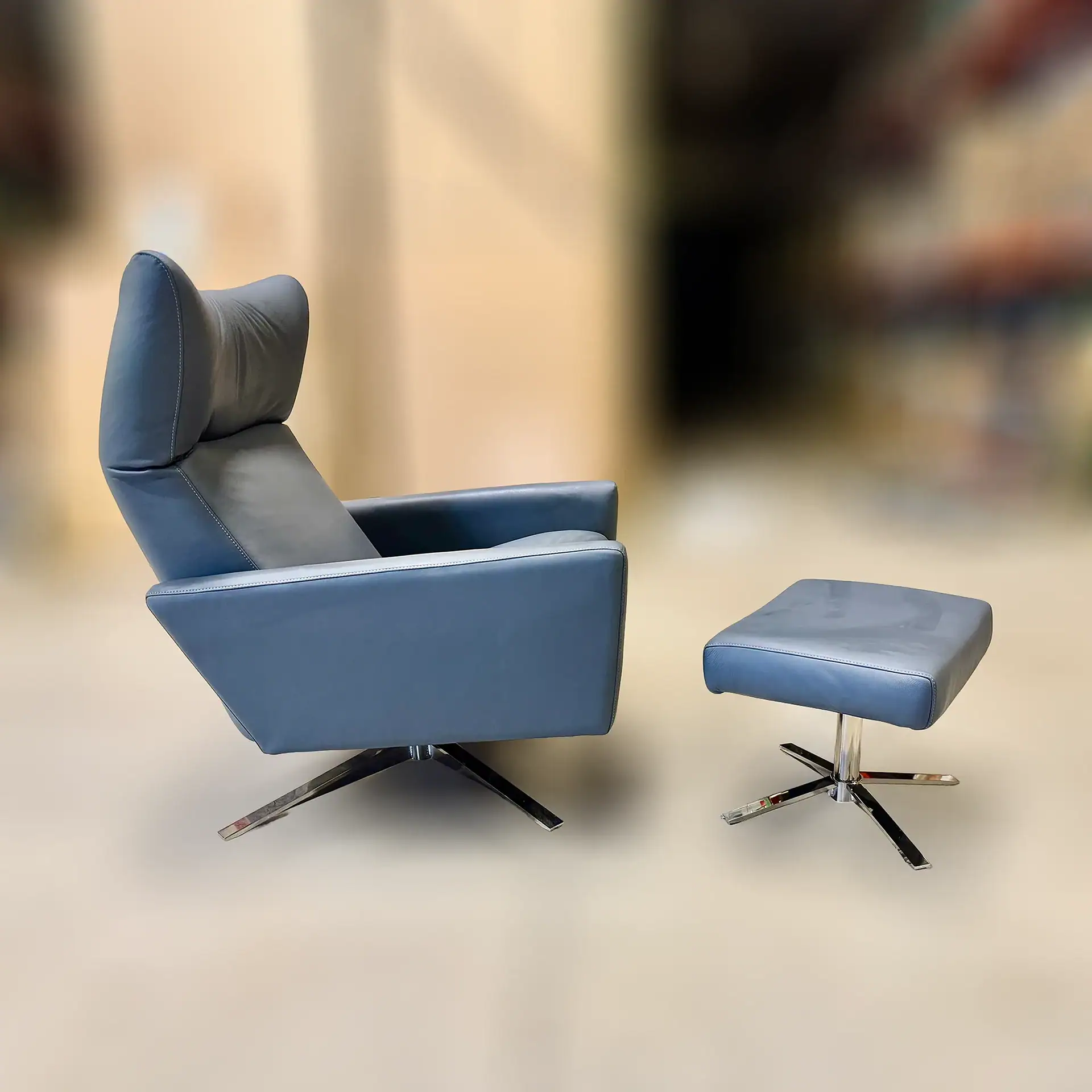 Blue leather lounge chair with matching ottoman in modern design.