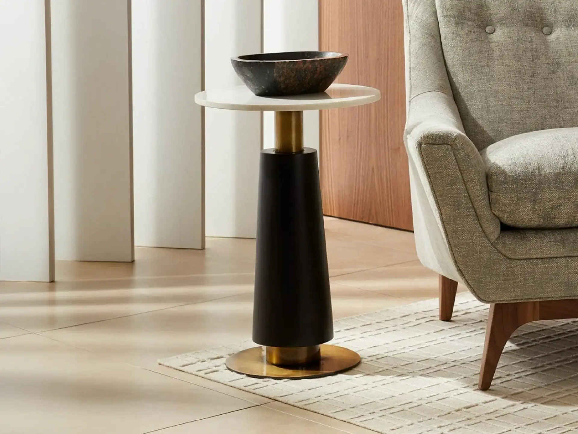 Contemporary side table with black base, gold accents, and white top in stylish living room.
