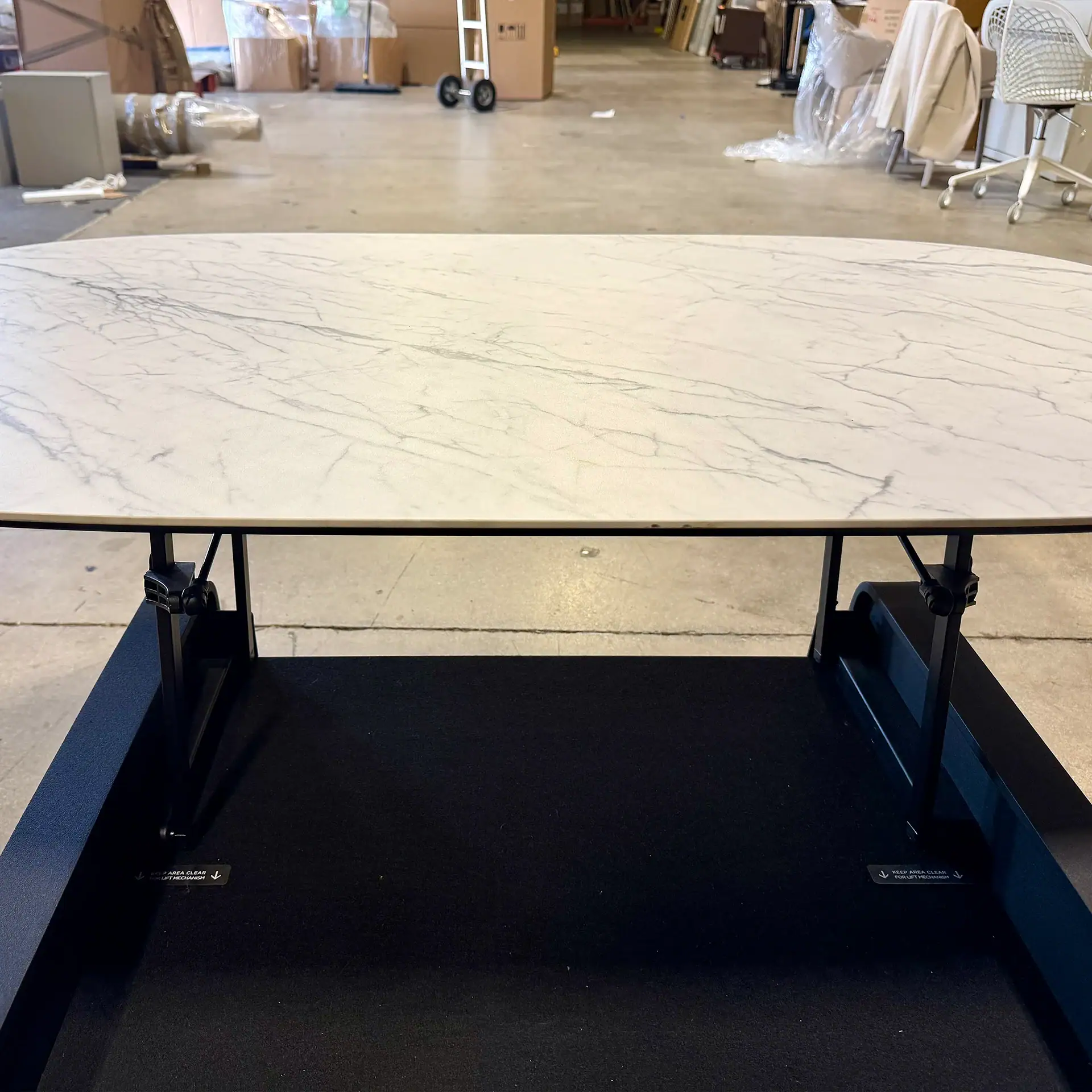 Modern lift coffee table with marble top and black base in showroom.