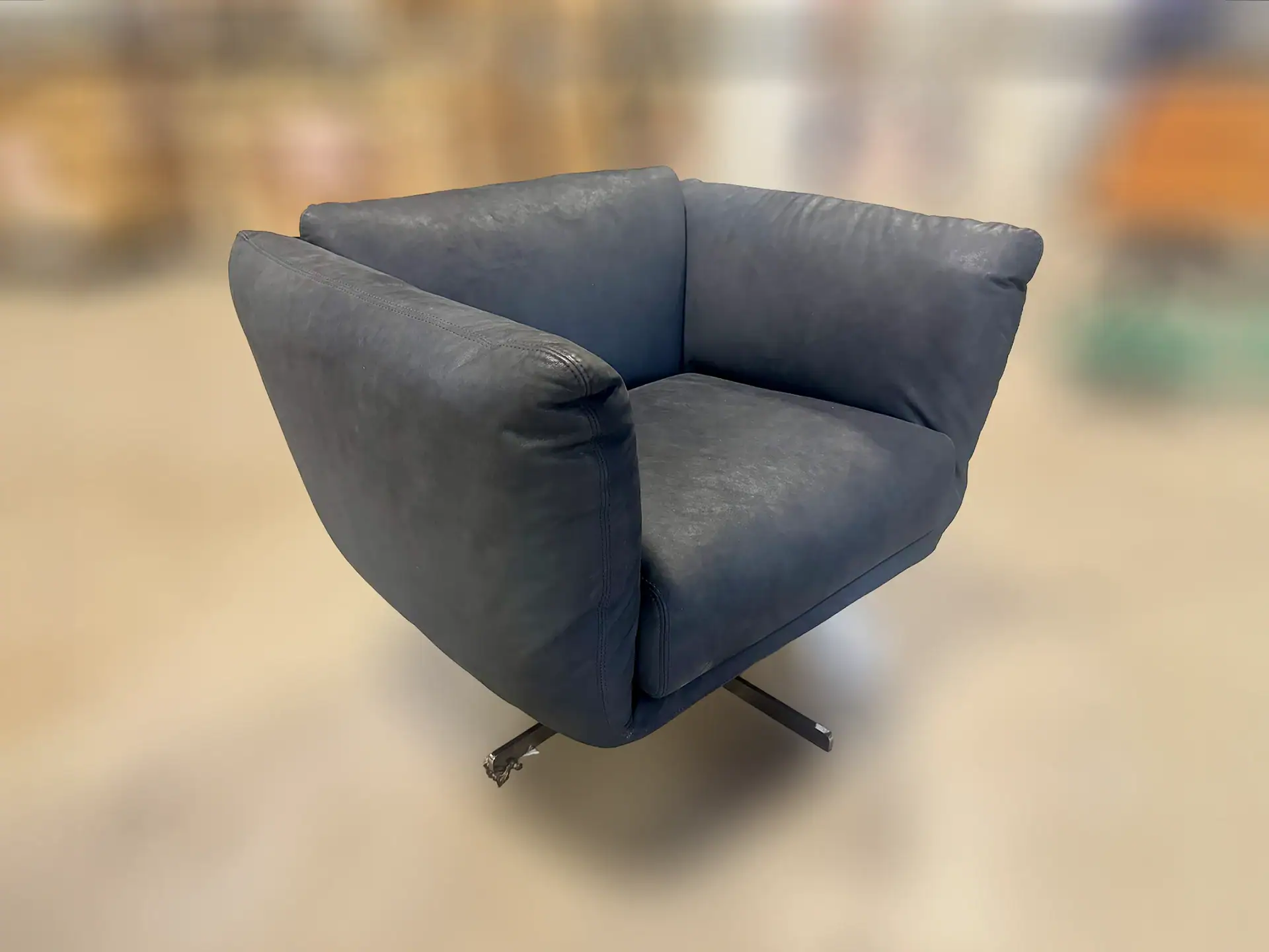 Modern swivel armchair with plush blue upholstery and rounded arms.