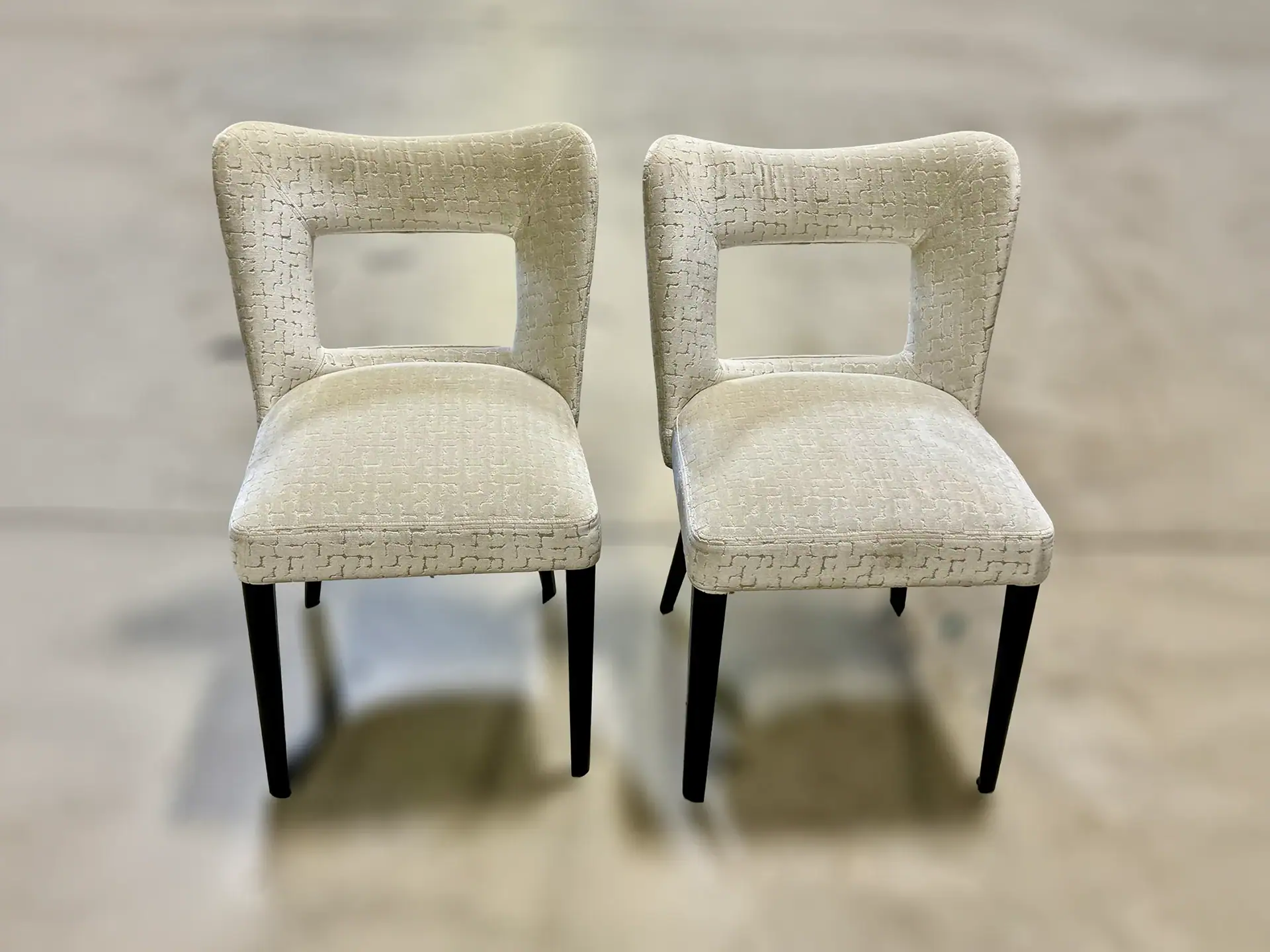 Elegant dining chairs with cream upholstery and black legs.