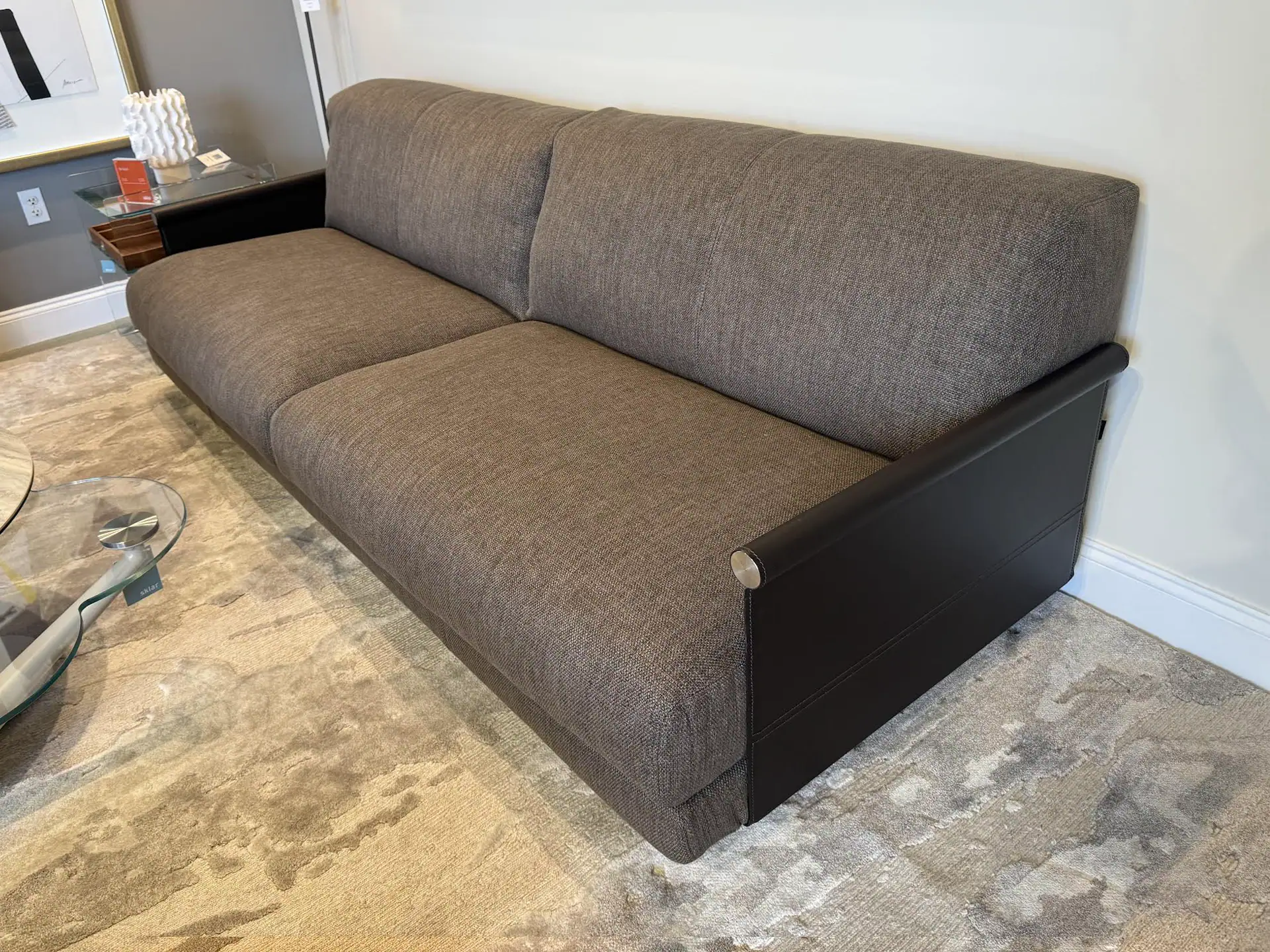 Modern grey fabric sofa with black wooden armrests, perfect for contemporary living rooms.