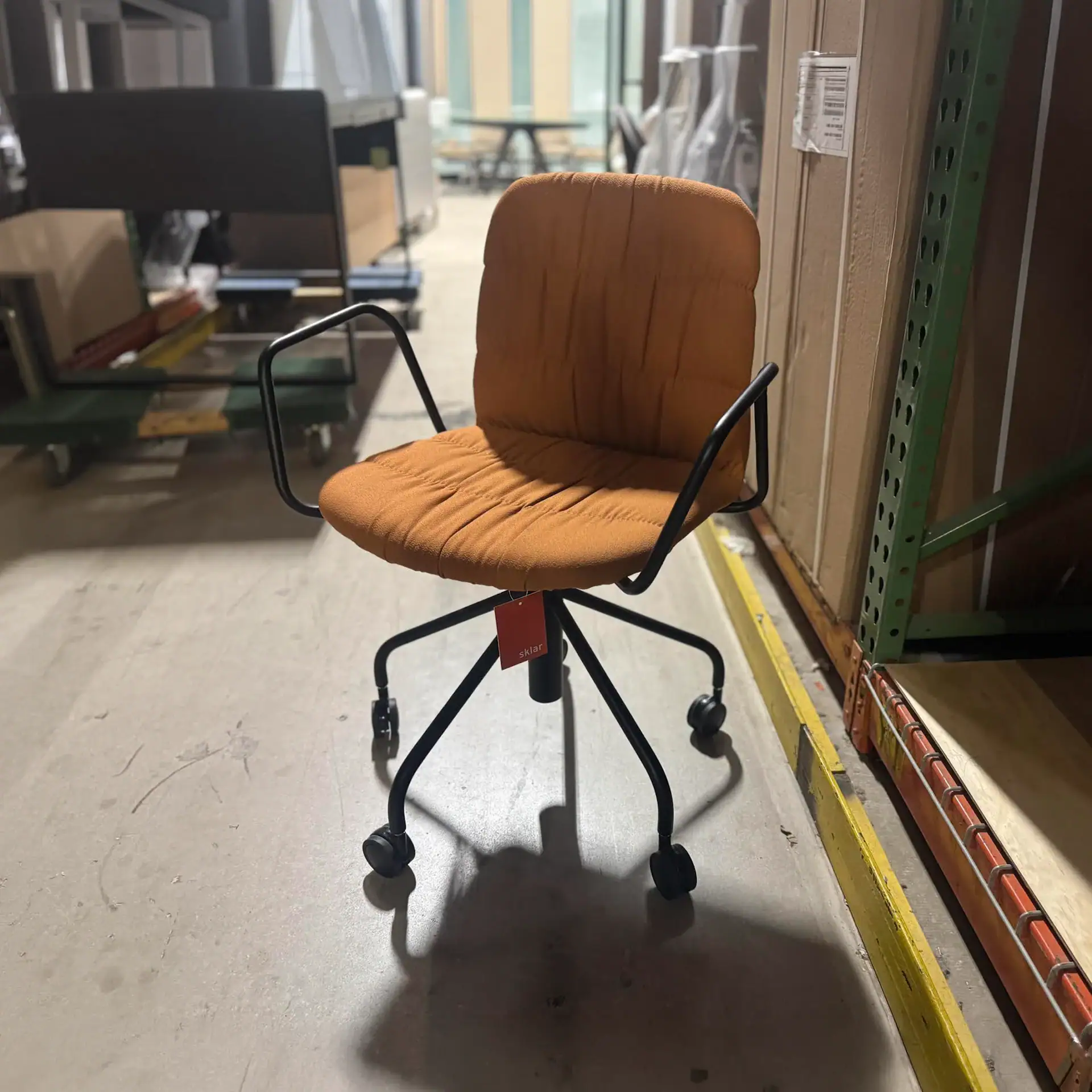Modern orange Midj Liù armchair with black metal frame and casters.