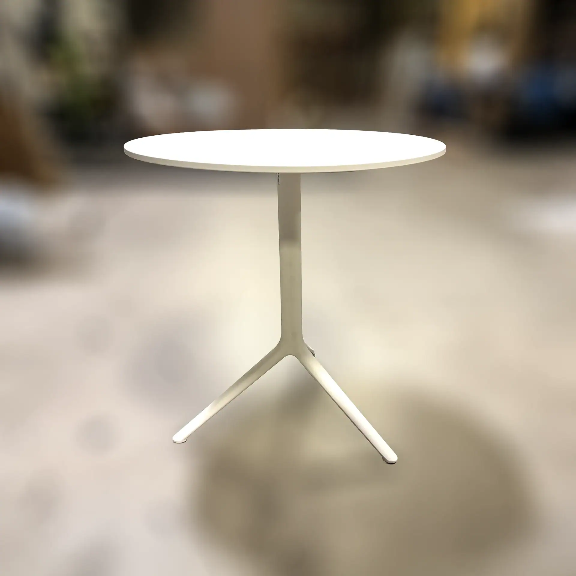 Modern white outdoor table with tripod base for patio or garden.
