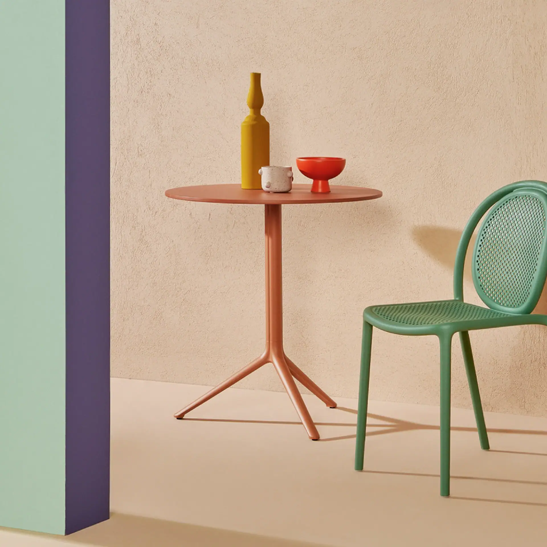 Pedrali Elliot outdoor table with colorful decor and green chair in modern setting.
