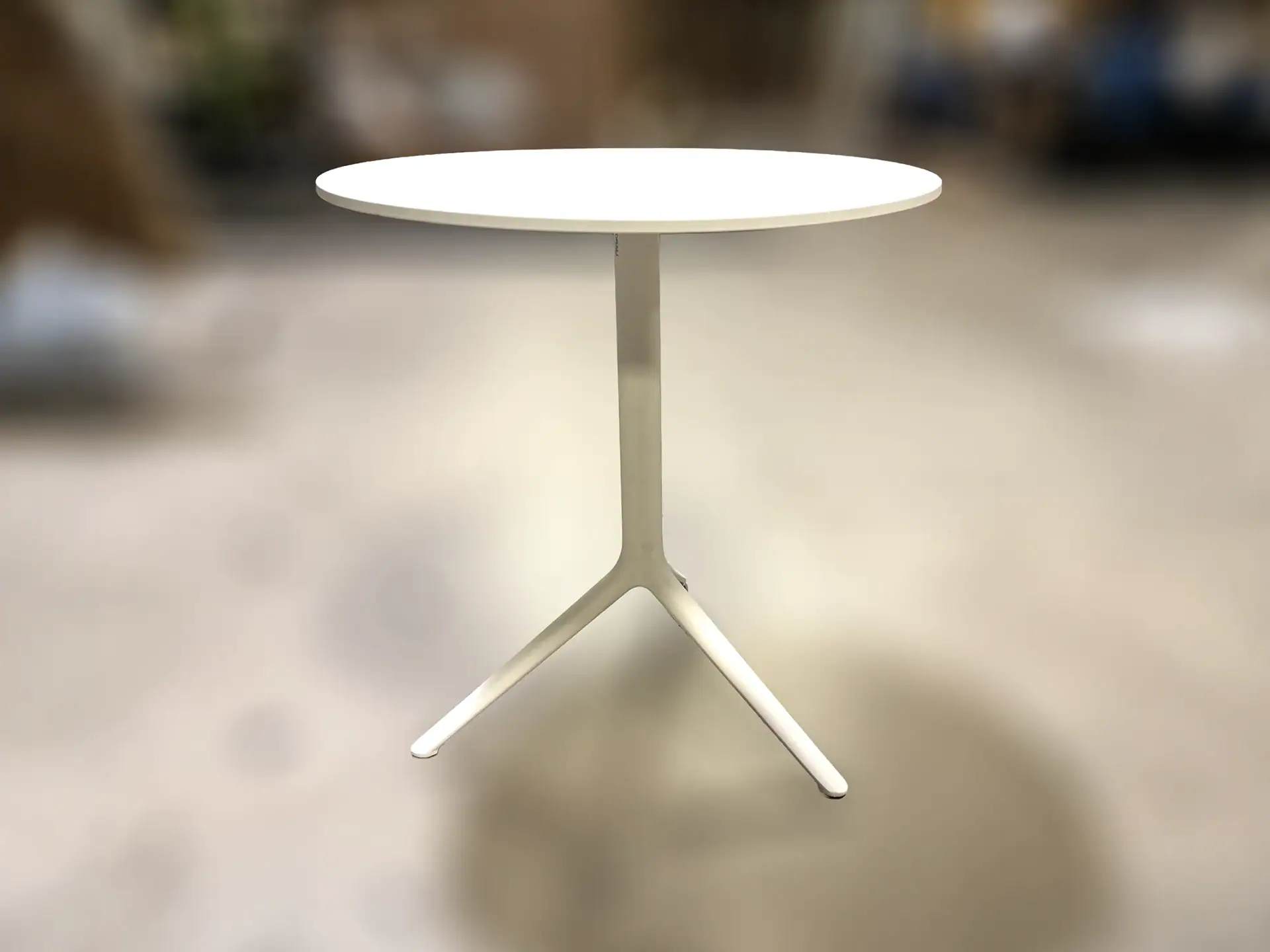 Modern white outdoor table with tripod base for patio or garden.