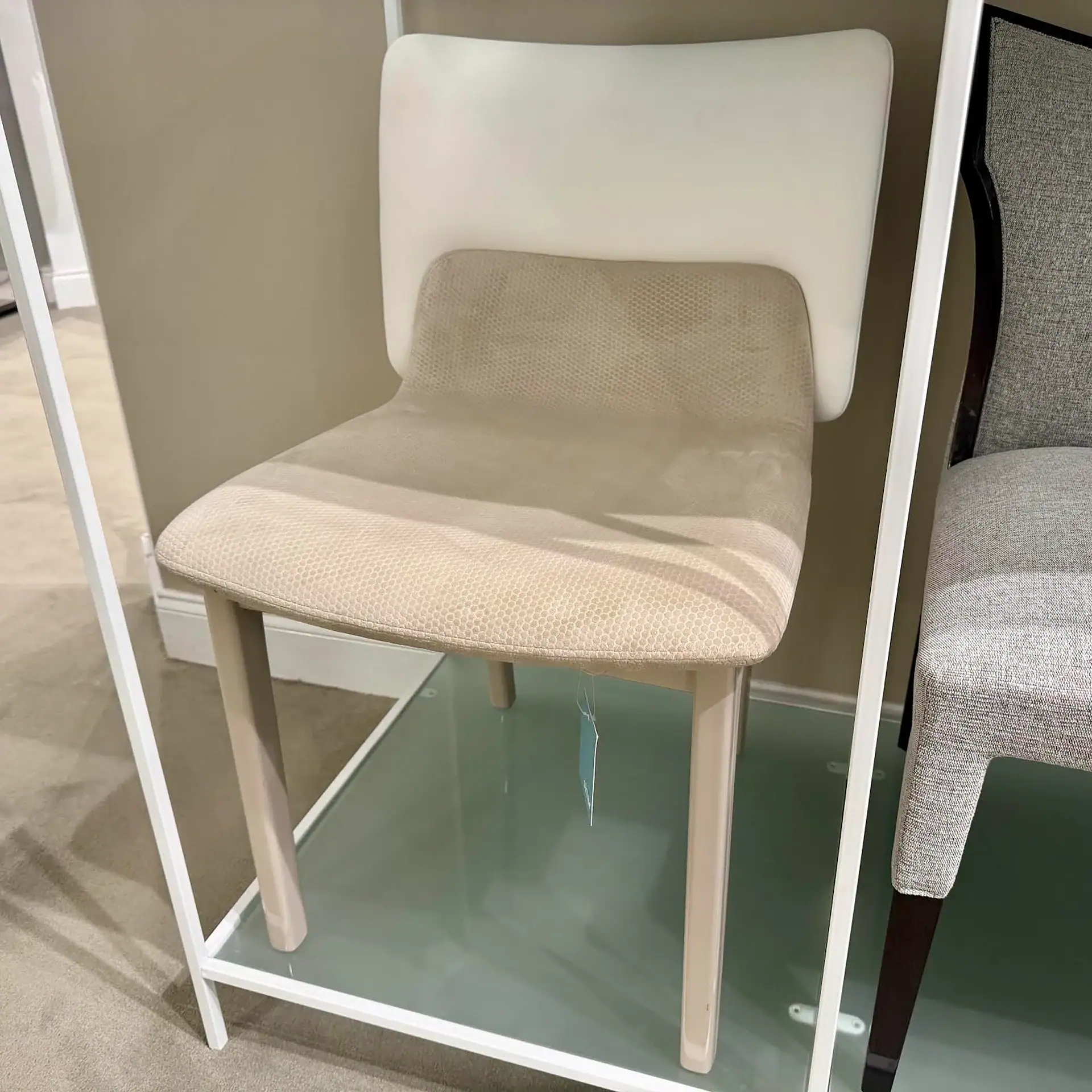 Upholstered dining chair featuring a beige fabric seat and a white backrest, supported by light wood.