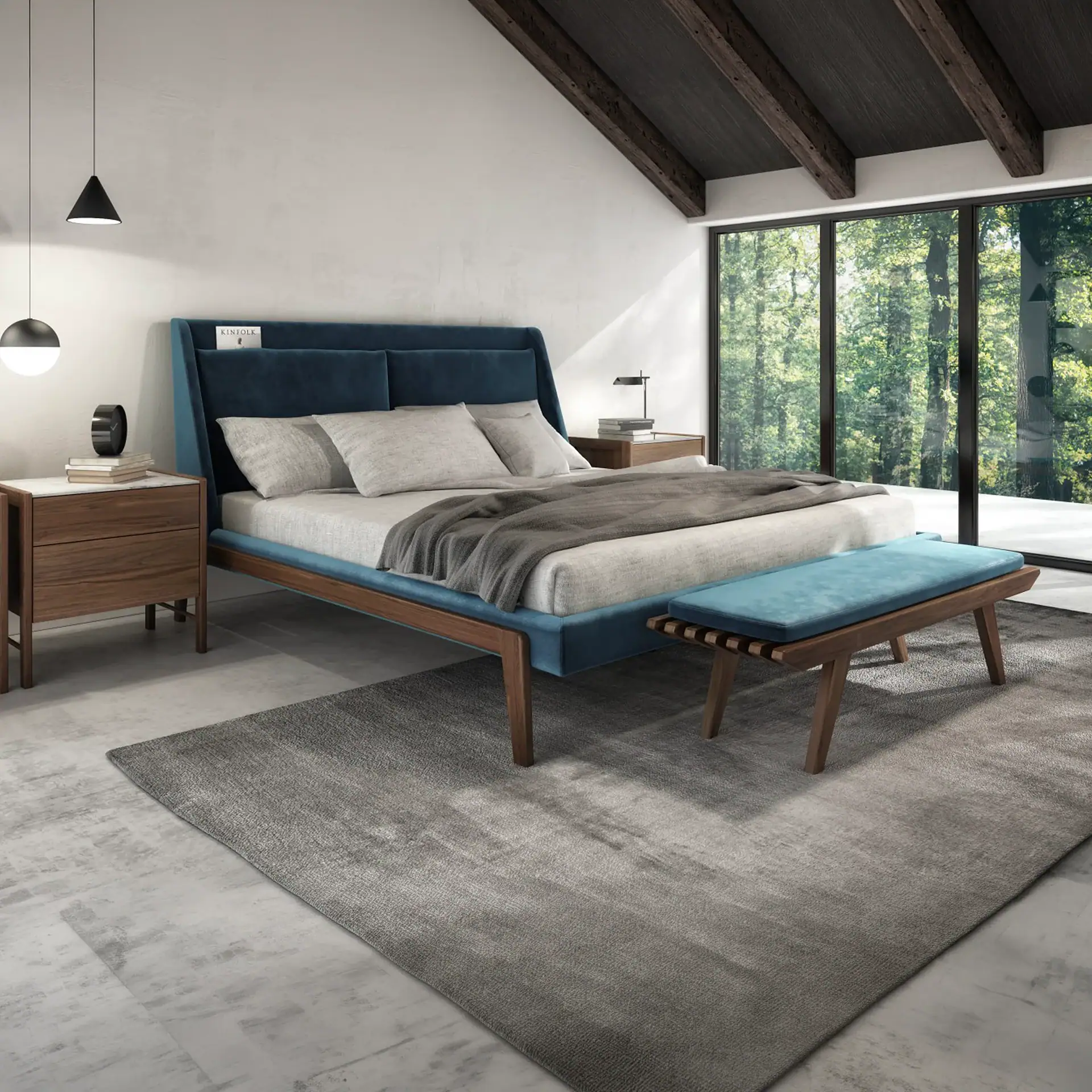 A modern bedroom with a blue upholstered bed, wooden nightstands, a gray rug, and a large window overlooking a forest.
