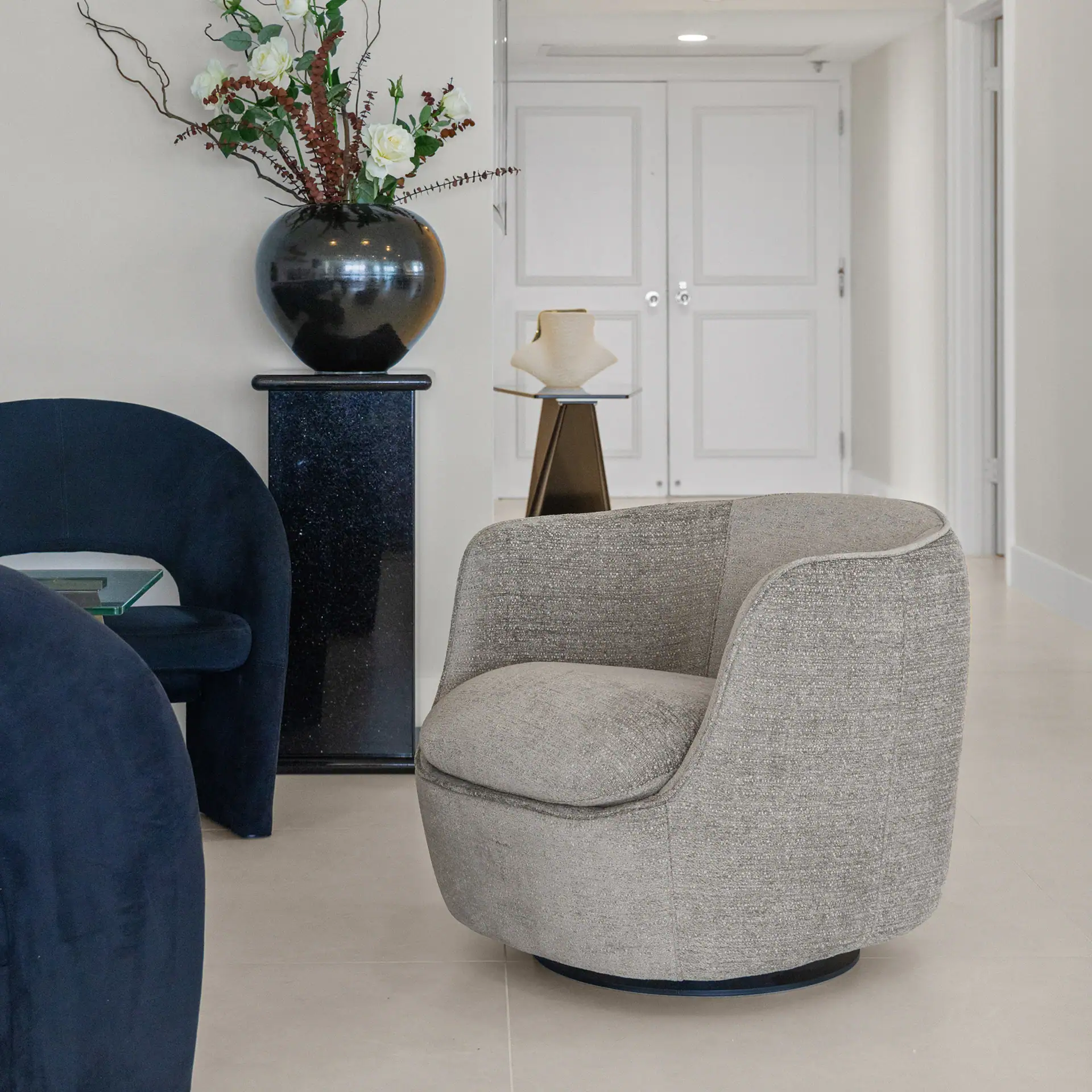 Contemporary living room featuring stylish armchair, floral arrangement, and minimalist decor.