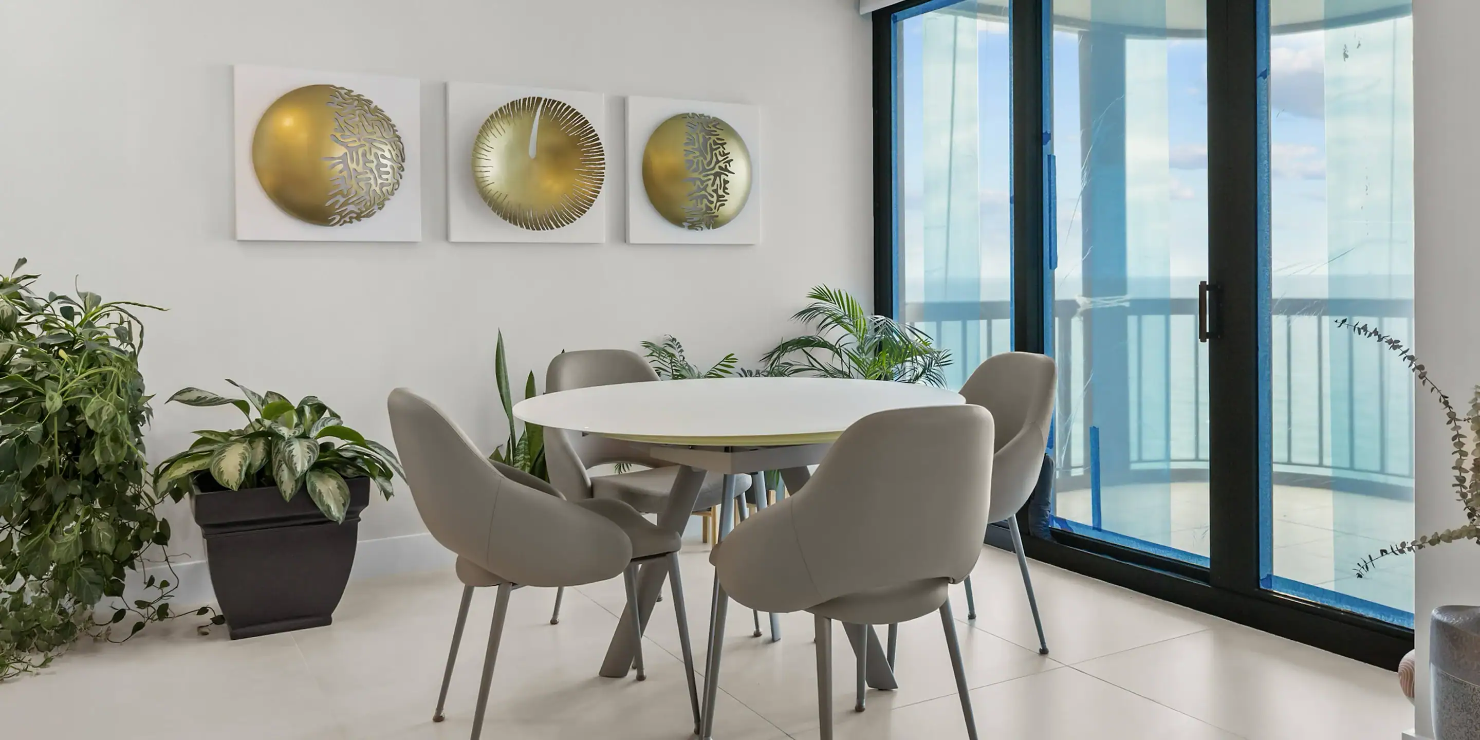 Modern round dining table with six upholstered chairs in a bright, contemporary interior.
