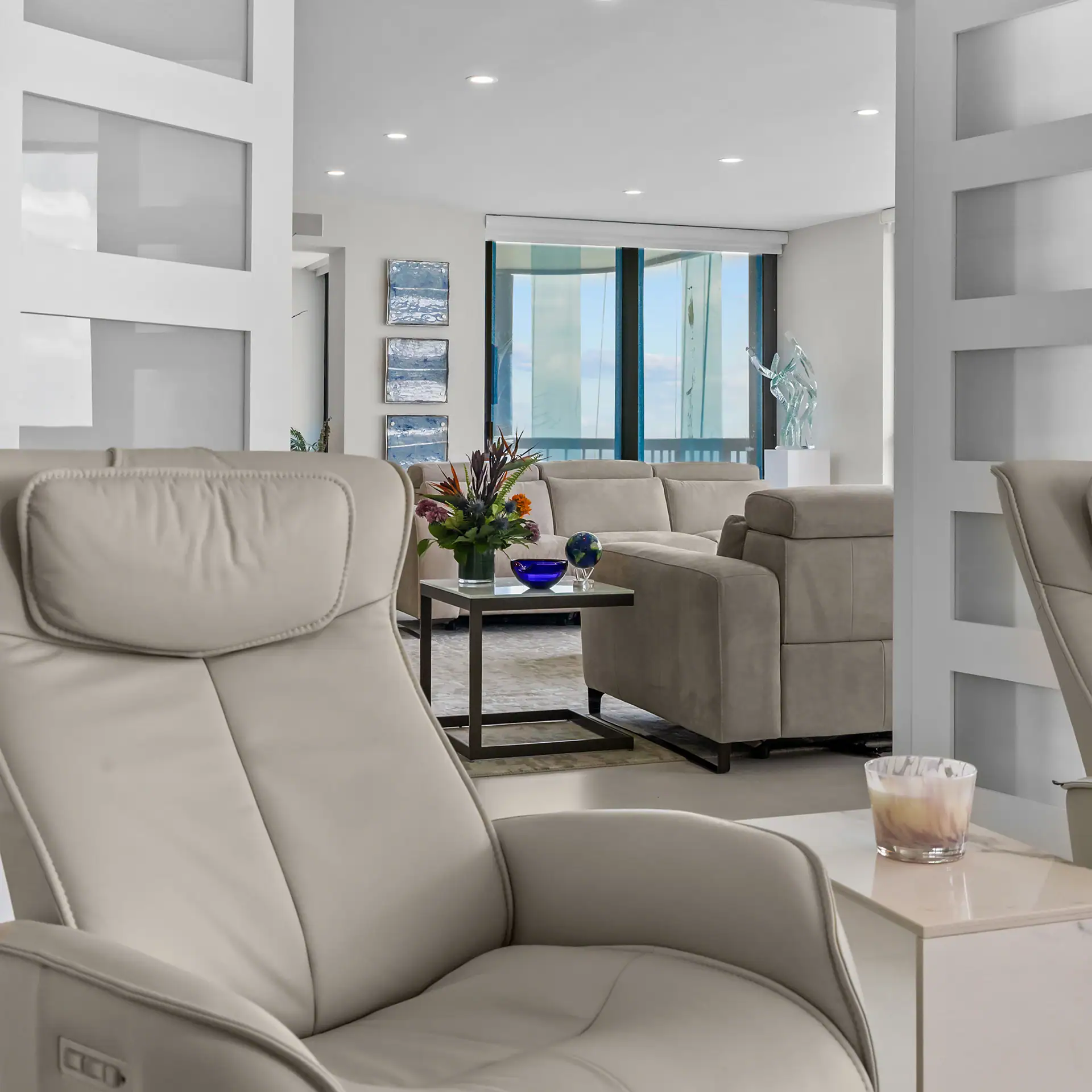 Elegant modern living room with plush beige sofas and large windows overlooking the ocean. Stylish d.