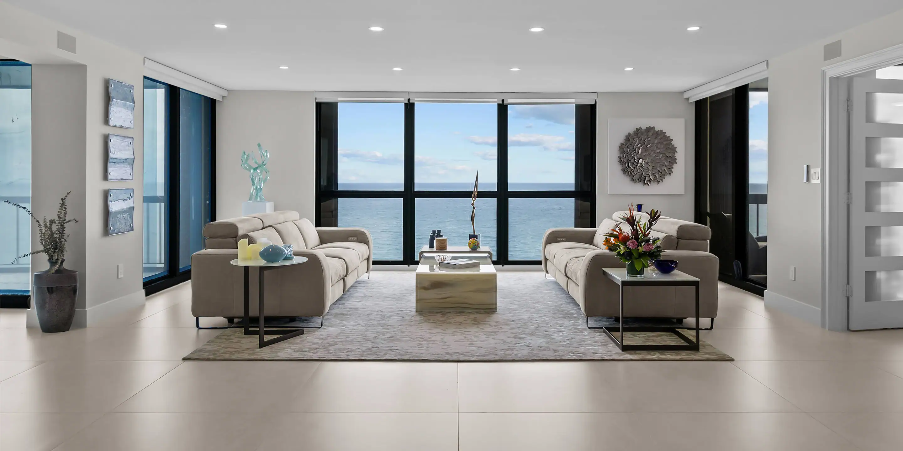 Modern living room with large windows overlooking the ocean, featuring stylish sofas, contemporary d.