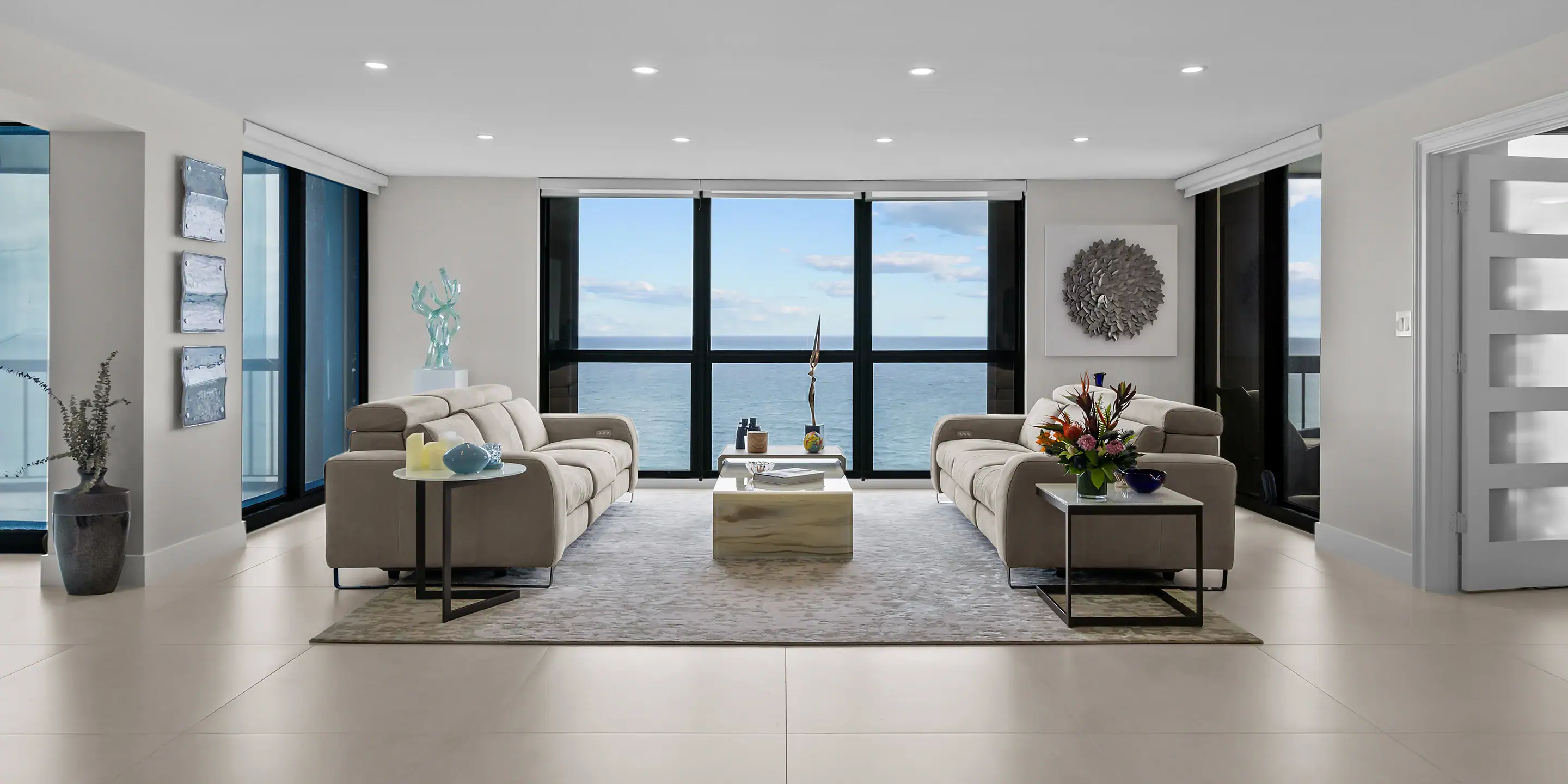 Modern living room with large windows overlooking the ocean, featuring stylish sofas, contemporary d.