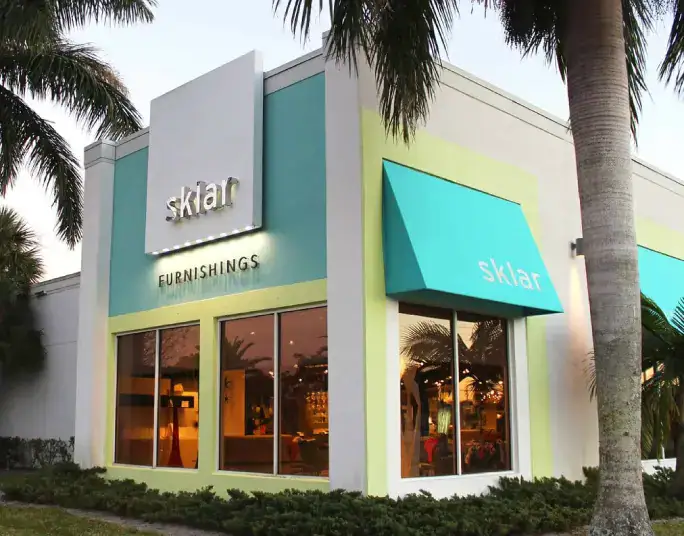 Modern Sklar Furnishings store with colorful exterior and large windows in a tropical setting.