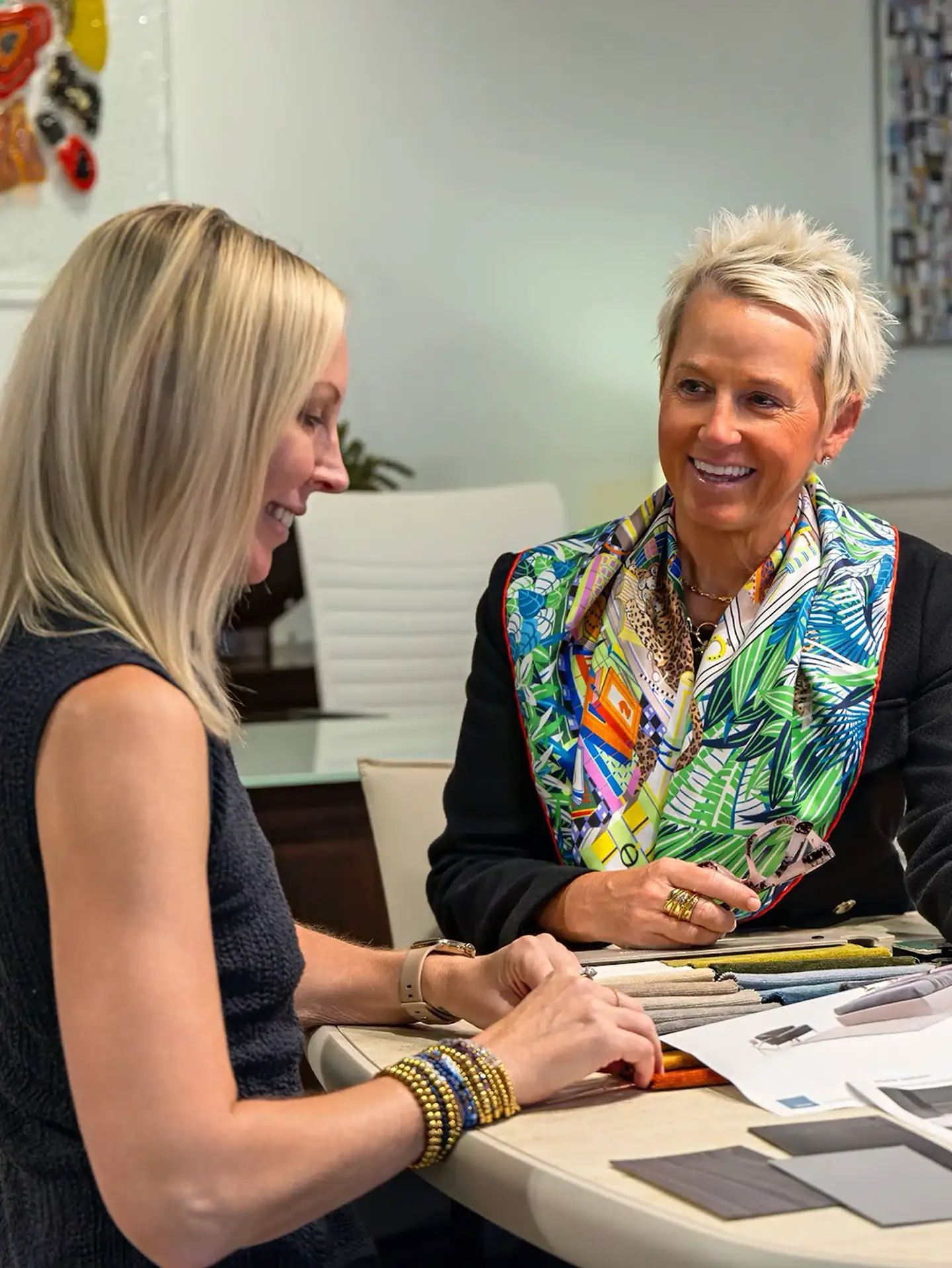 Bright, professional office meeting featuring two women discussing design options with colorful deco.