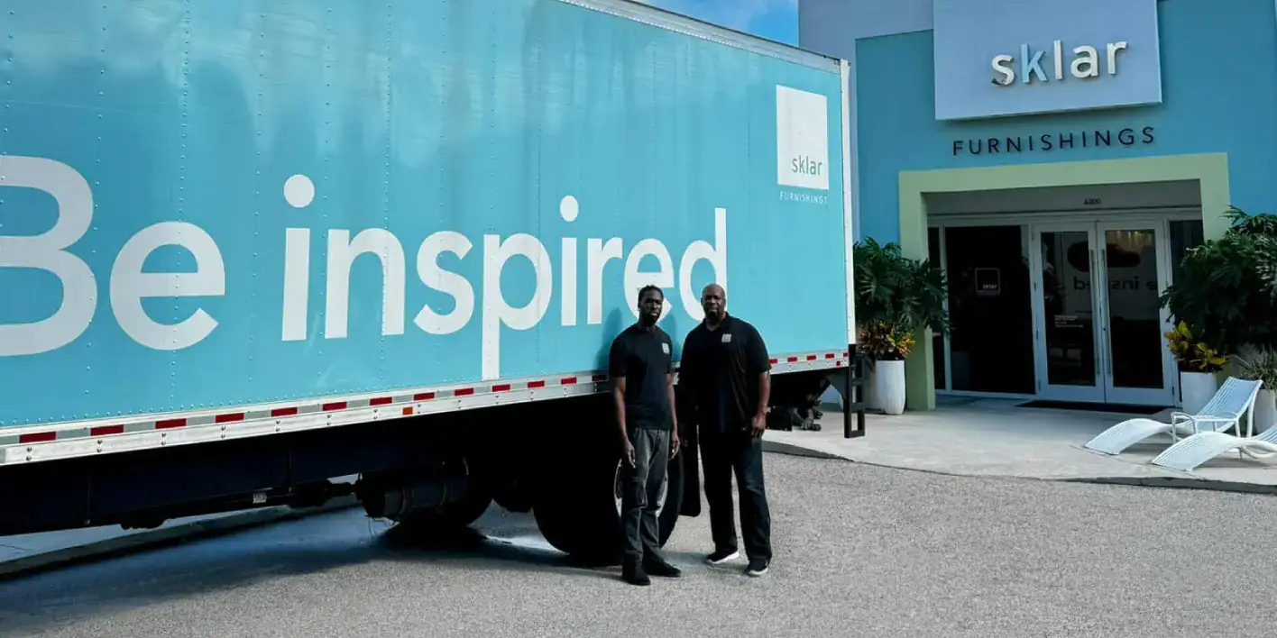 Delivery truck with Sklar Furnishings branding outside store.
