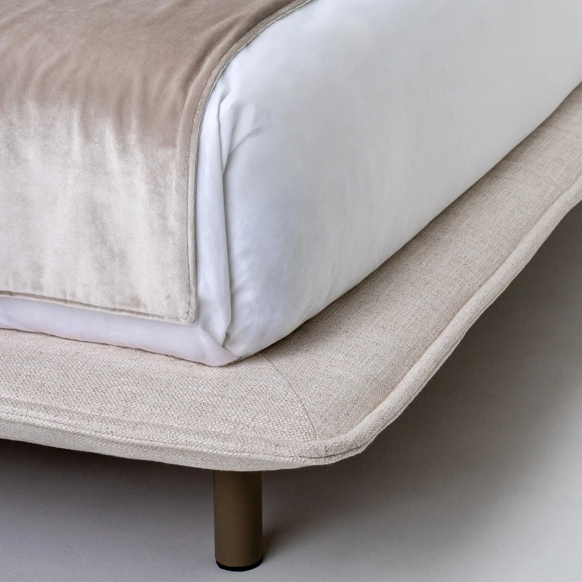 Close-up of Haven upholstered bed with beige fabric and metal leg.