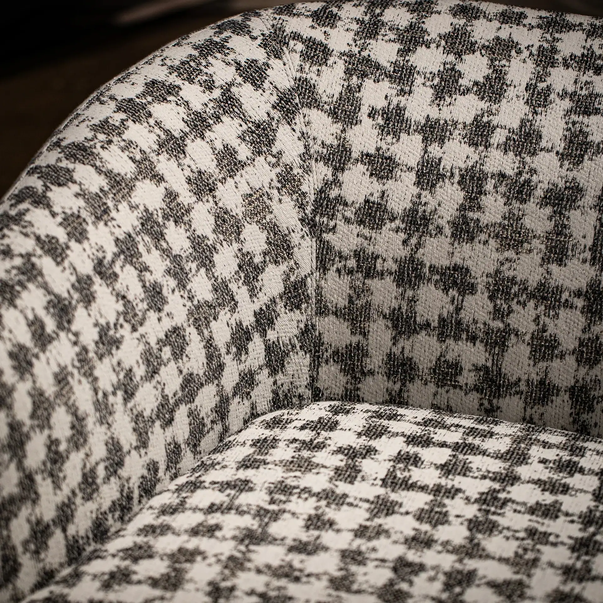 Close-up of a chair upholstered in a black and off-white houndstooth fabric.