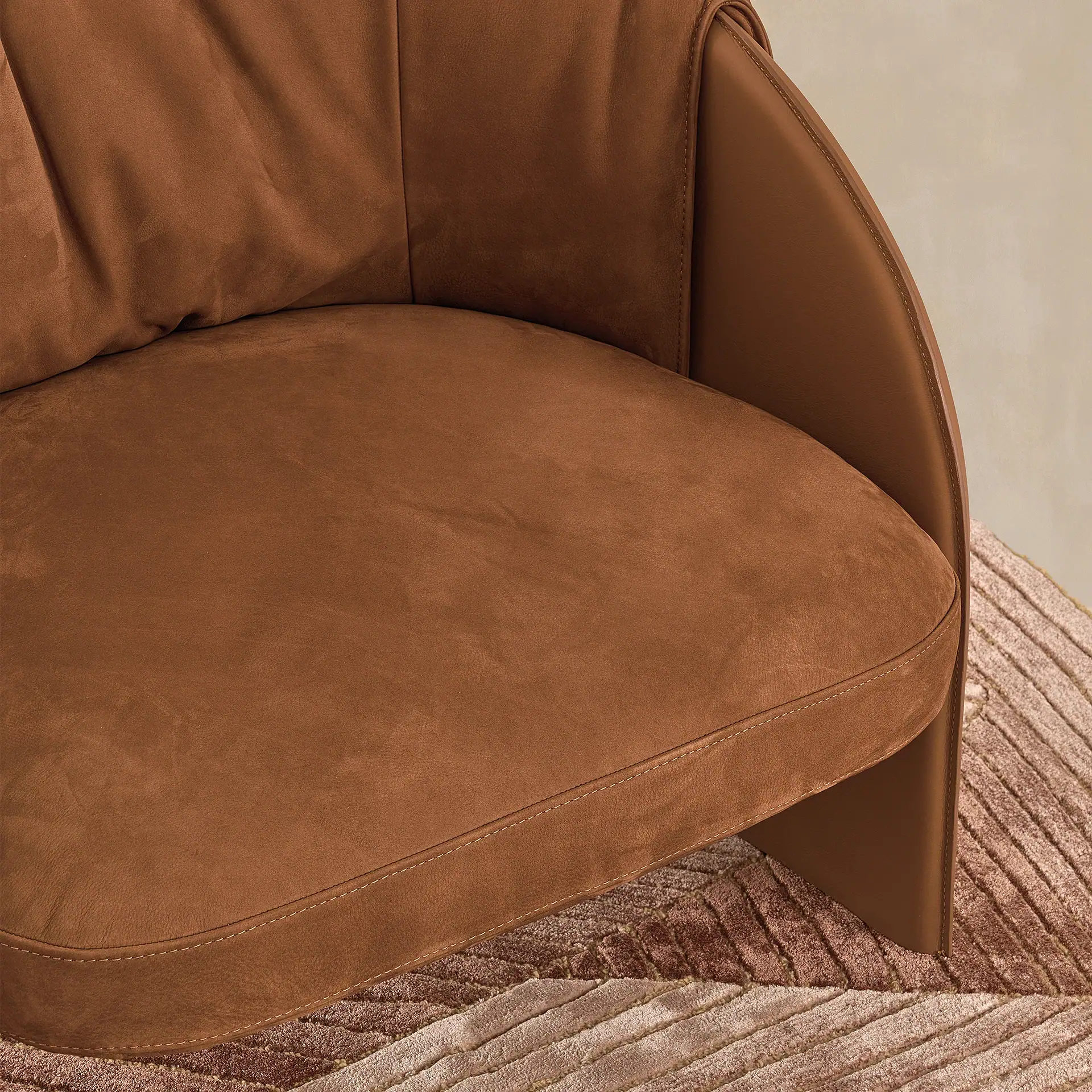 Close-up of a brown Bella armchair with curved design and plush upholstery.