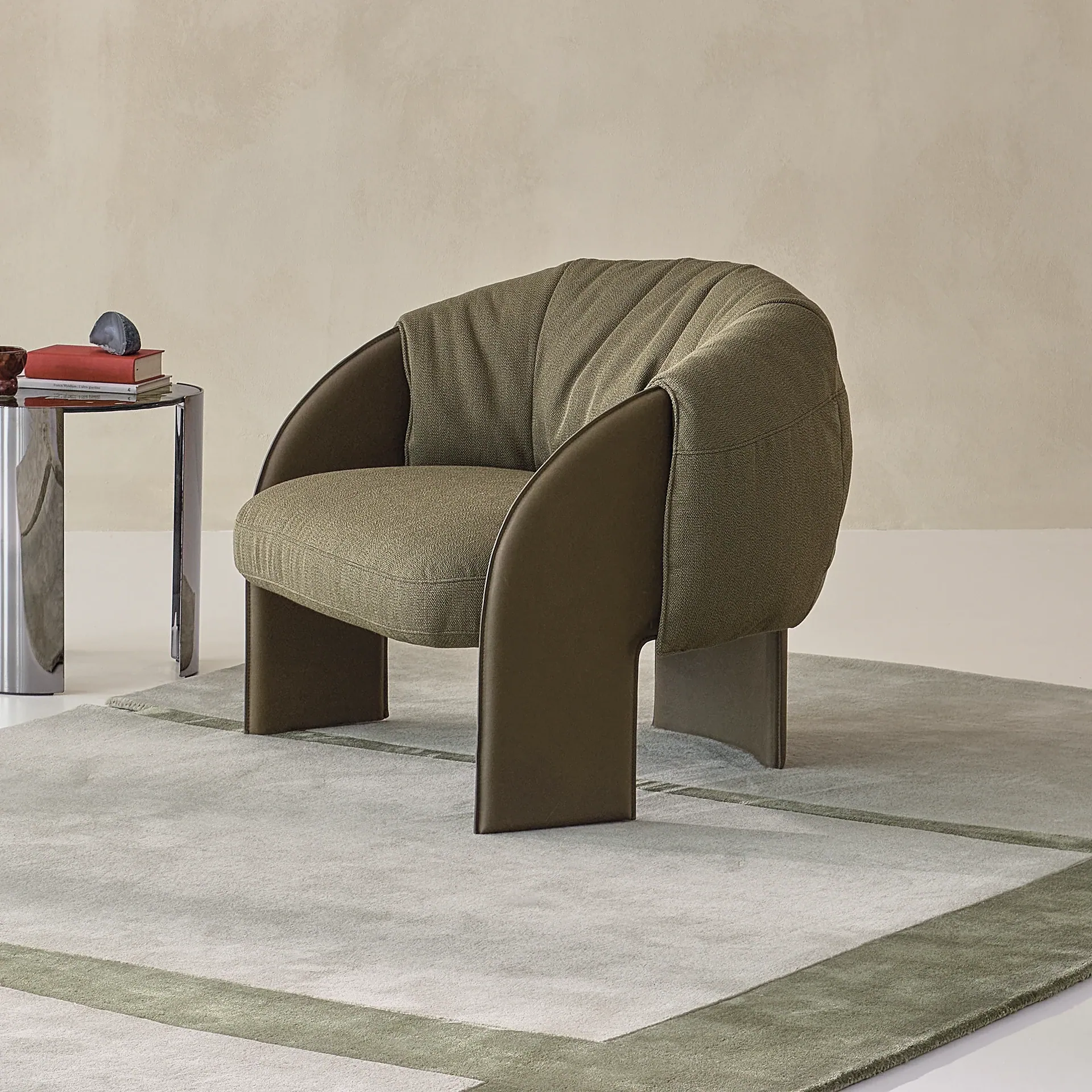 Sklar Armchair in olive upholstery with curved brown base in a minimalist setting.