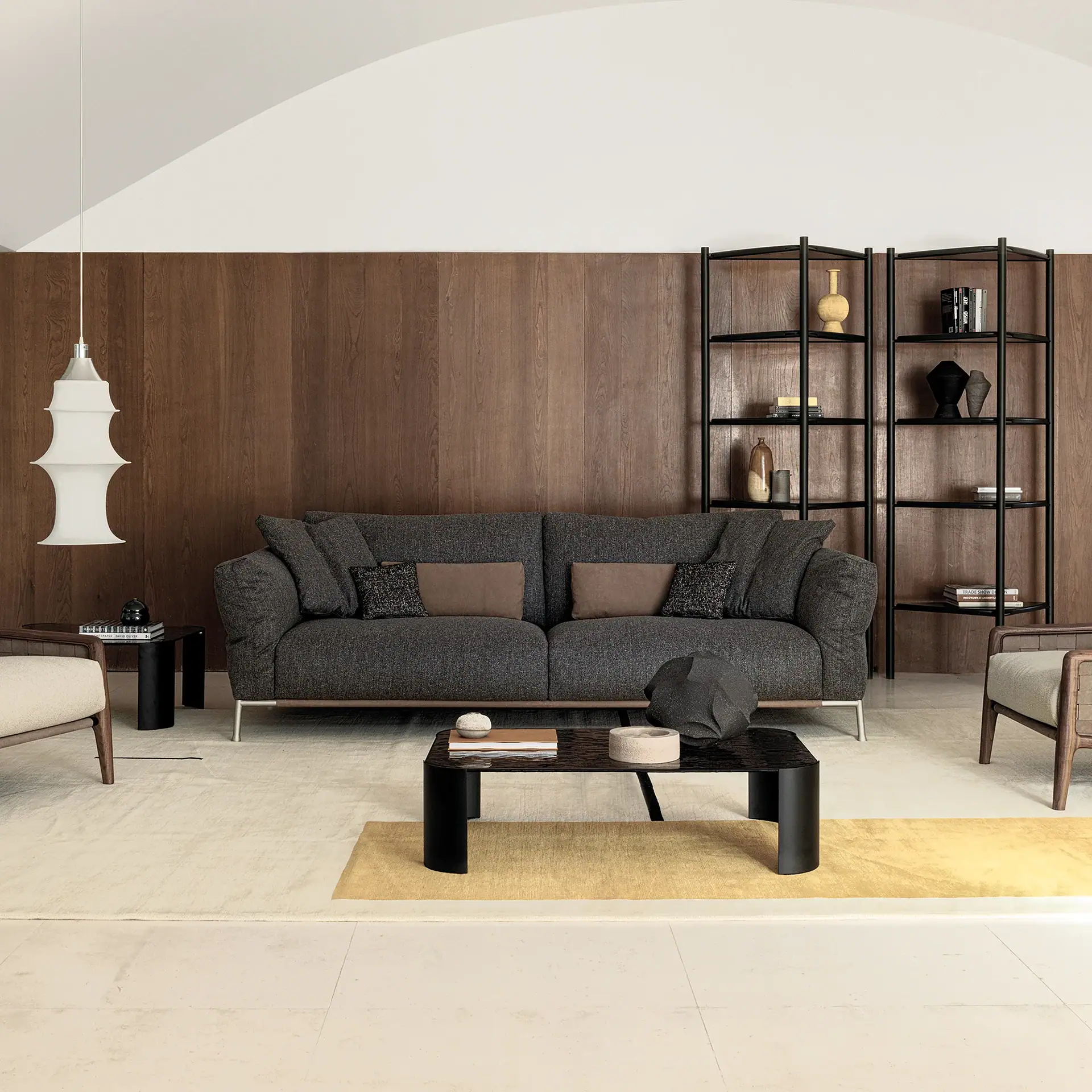 Contemporary living room with dark sofa, wooden wall, and black shelving unit.