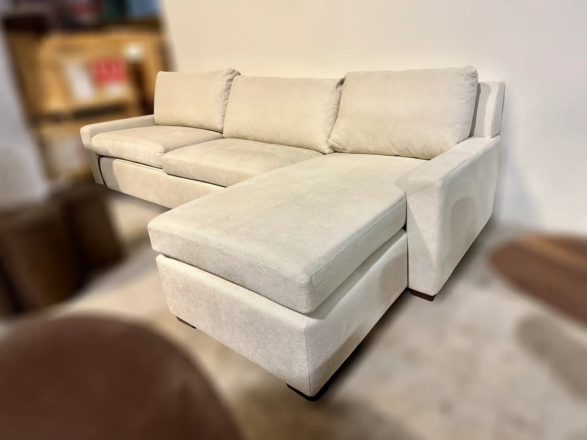 Modern beige sleeper sofa with chaise lounge and plush cushions.