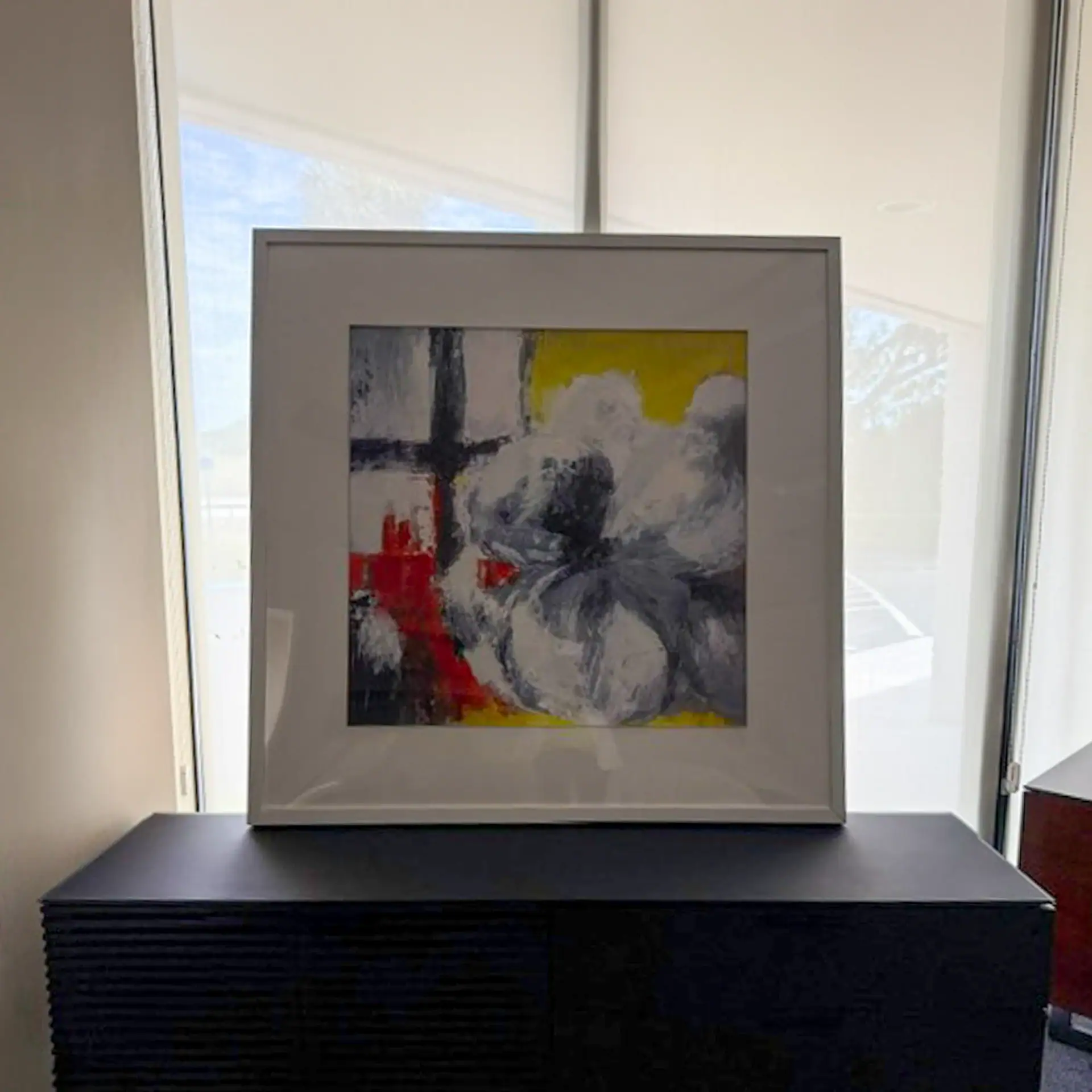 Abstract blue, yellow, red, and black wall art in a white frame.