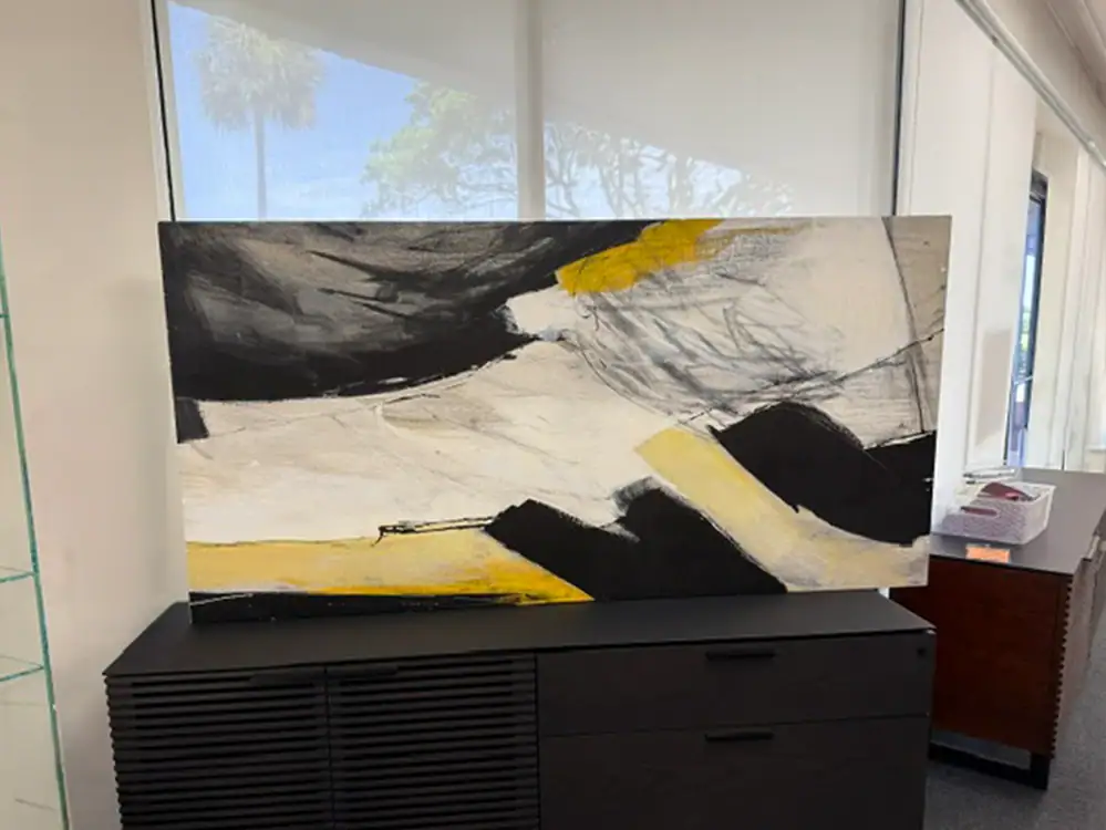 Abstract black, white, and yellow wall art piece in modern interior.