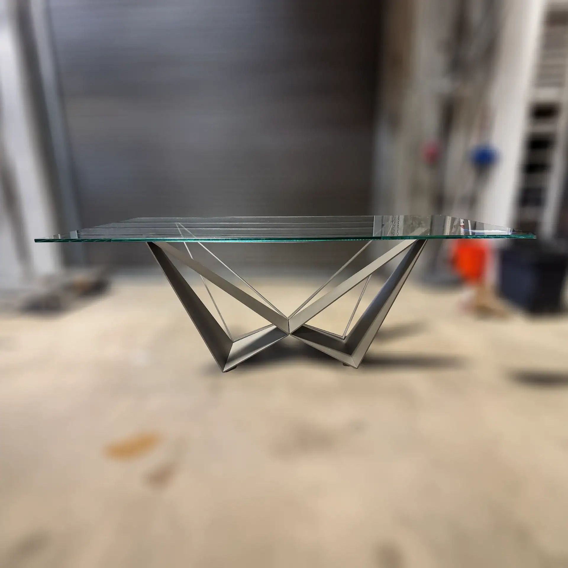 Contemporary glass dining table with geometric metal base design.