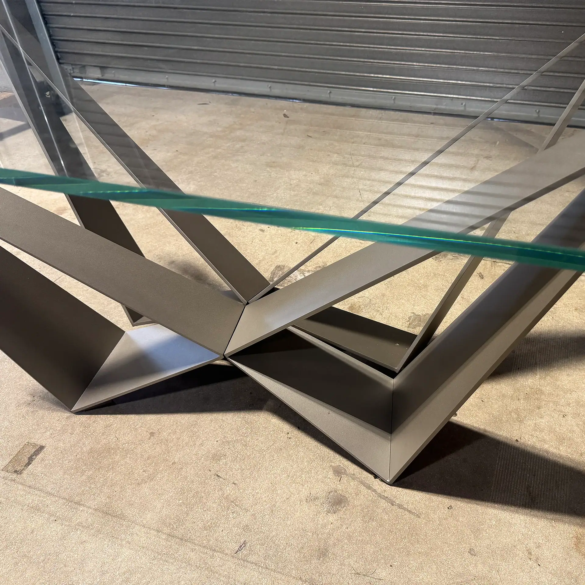 Contemporary glass and metal table with geometric base design.