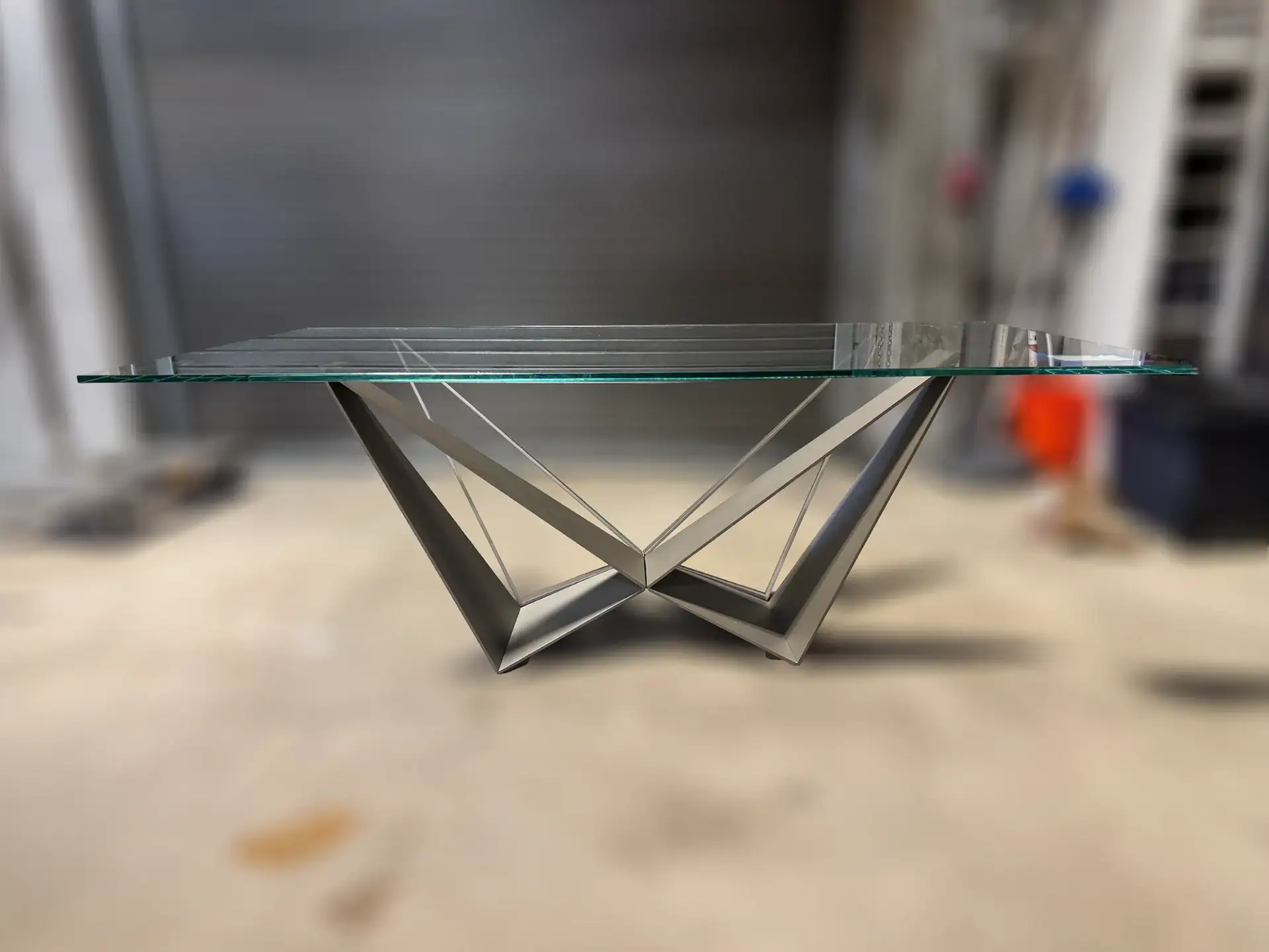 Modern glass dining table with geometric metal base design.