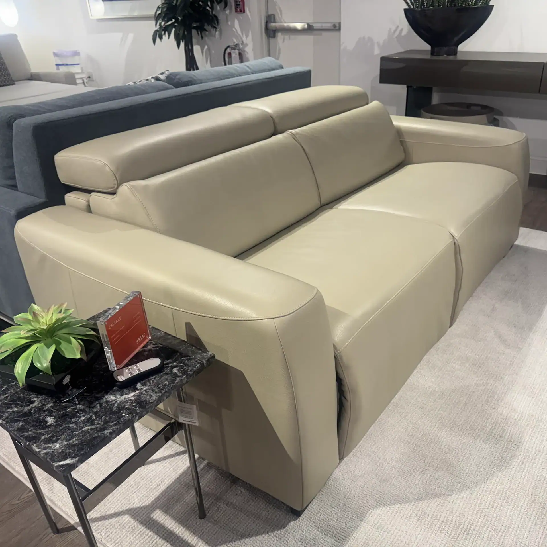 Beige leather sofa with adjustable headrests, stylish design, and comfortable seating for living roo.