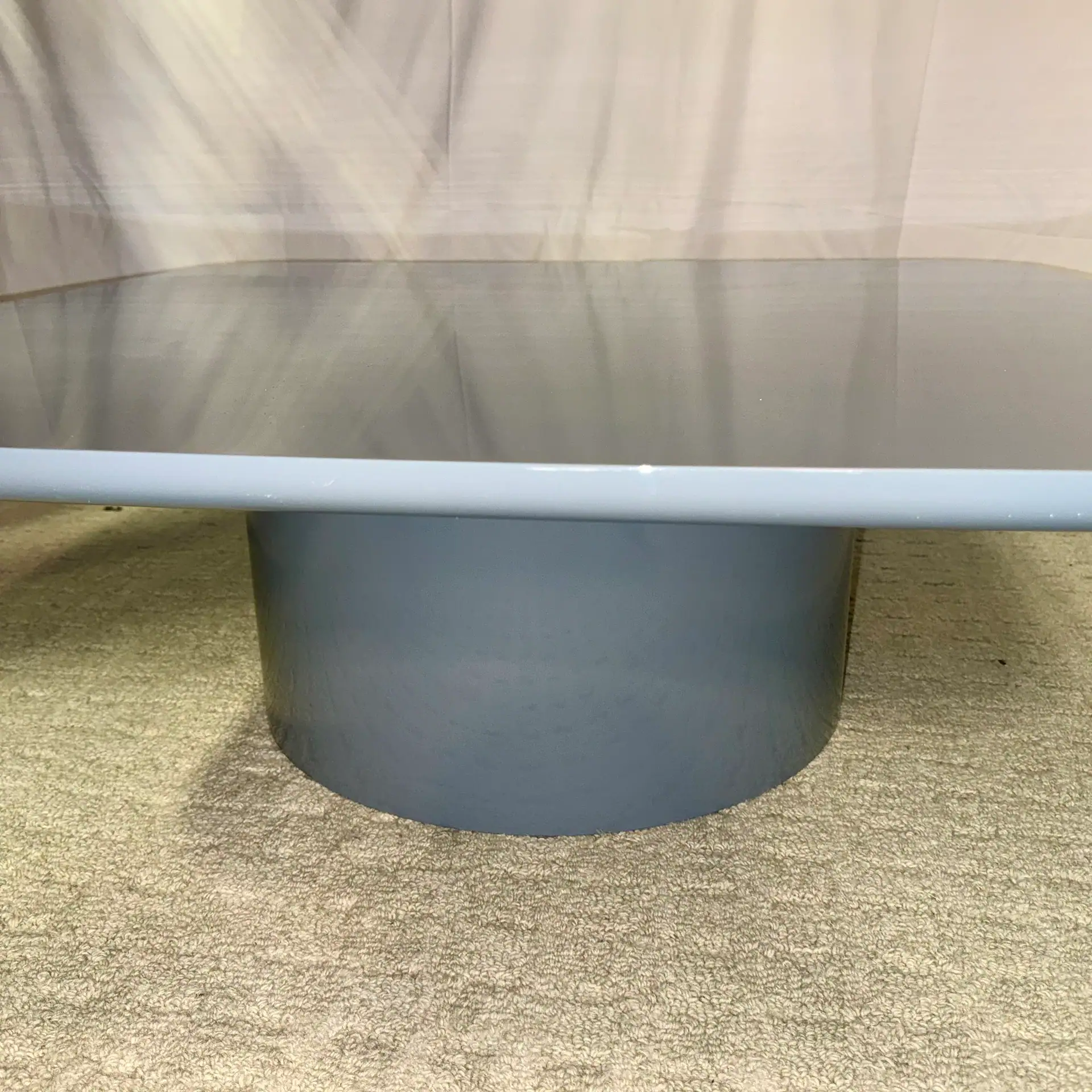 Modern round cocktail table with a smooth surface and cylindrical base.