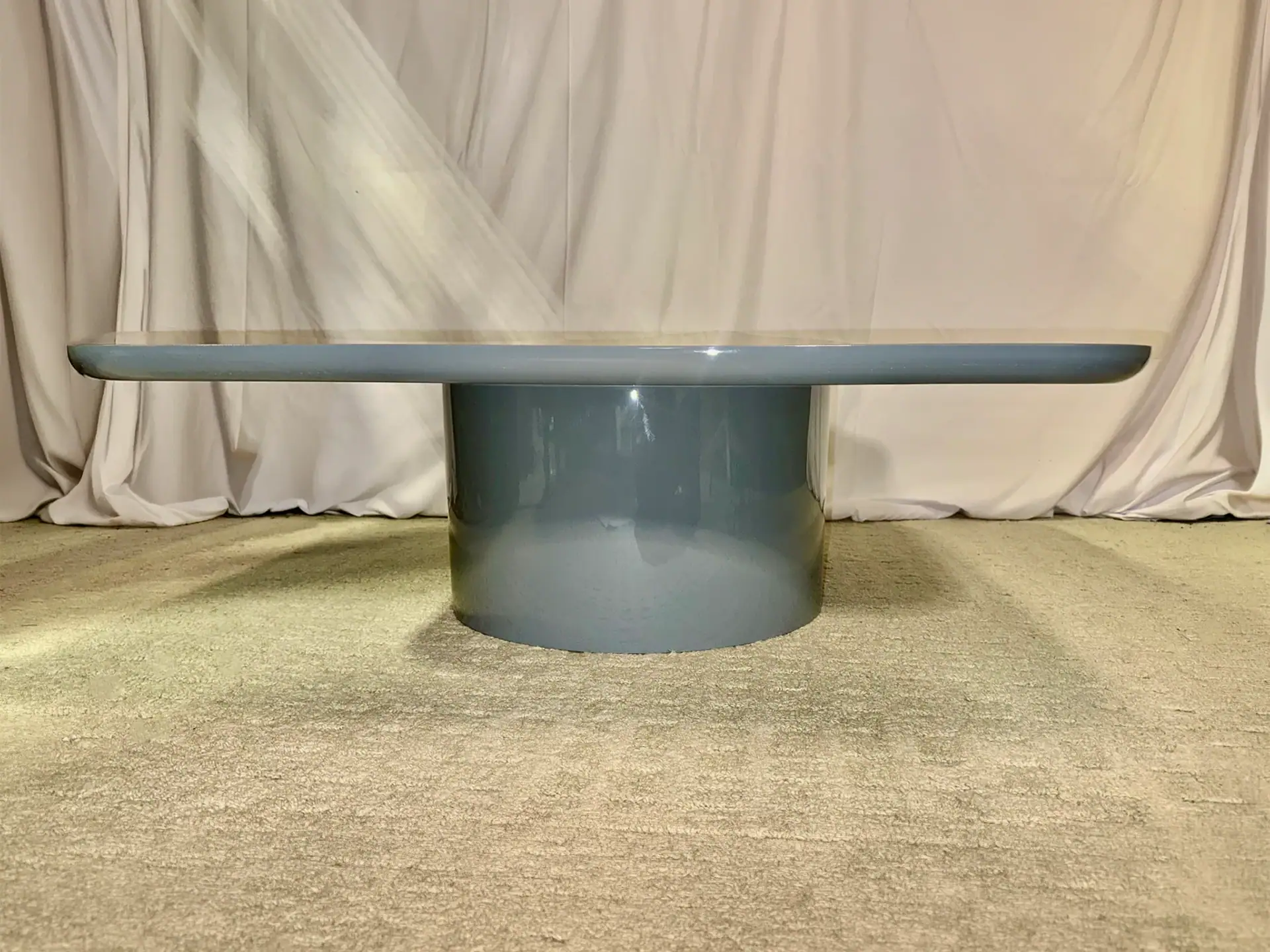 Modern blue cocktail table with a round base and sleek top for elegant living spaces.