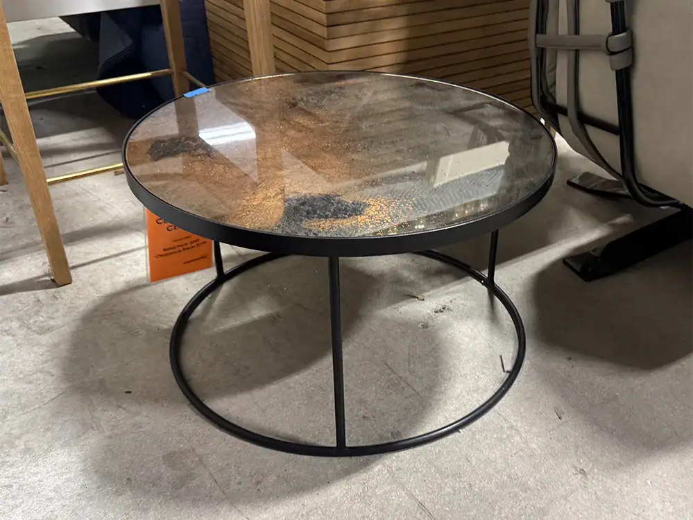 Round coffee table with glass top and black metal frame.