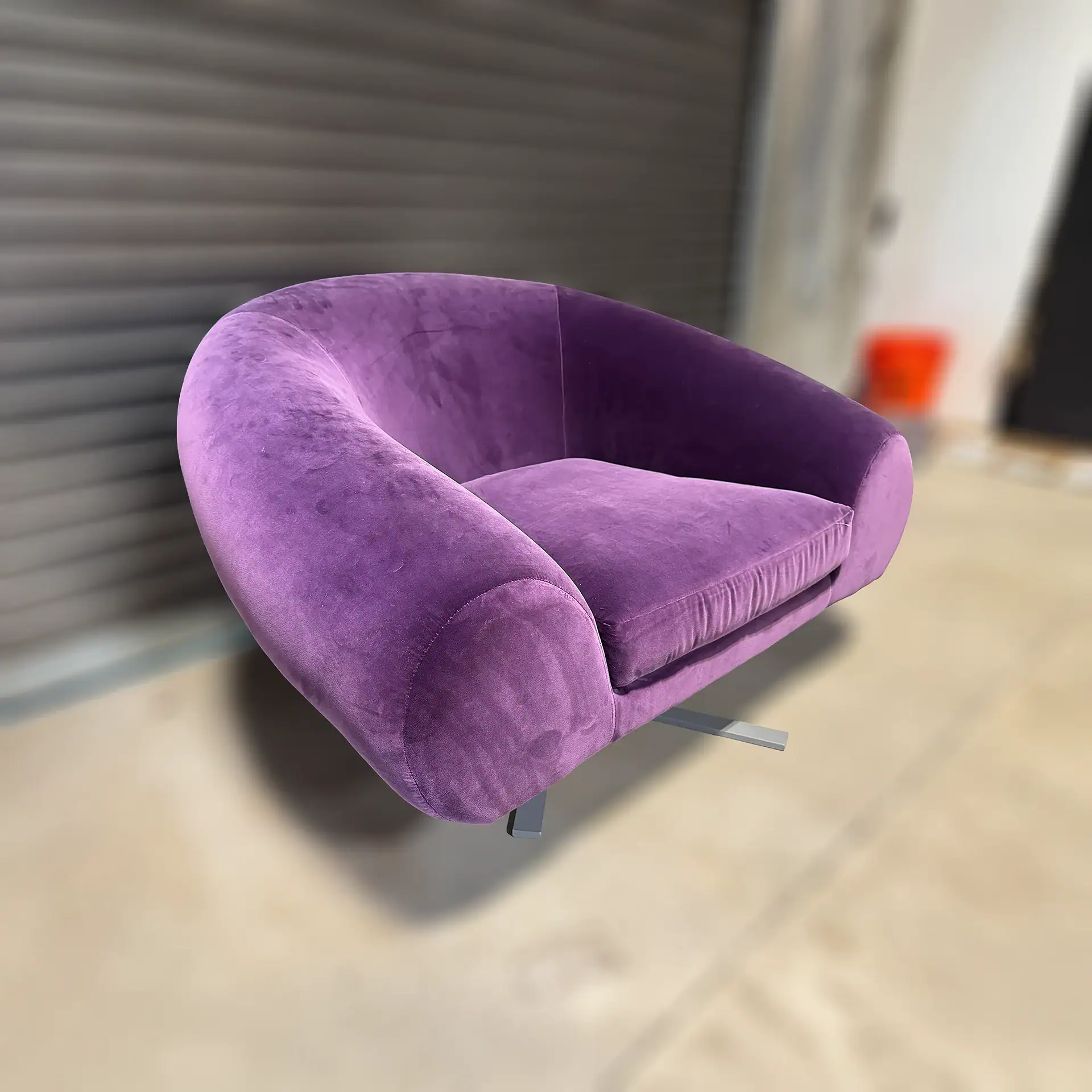 Purple velvet lounge chair with modern design and curved shape.