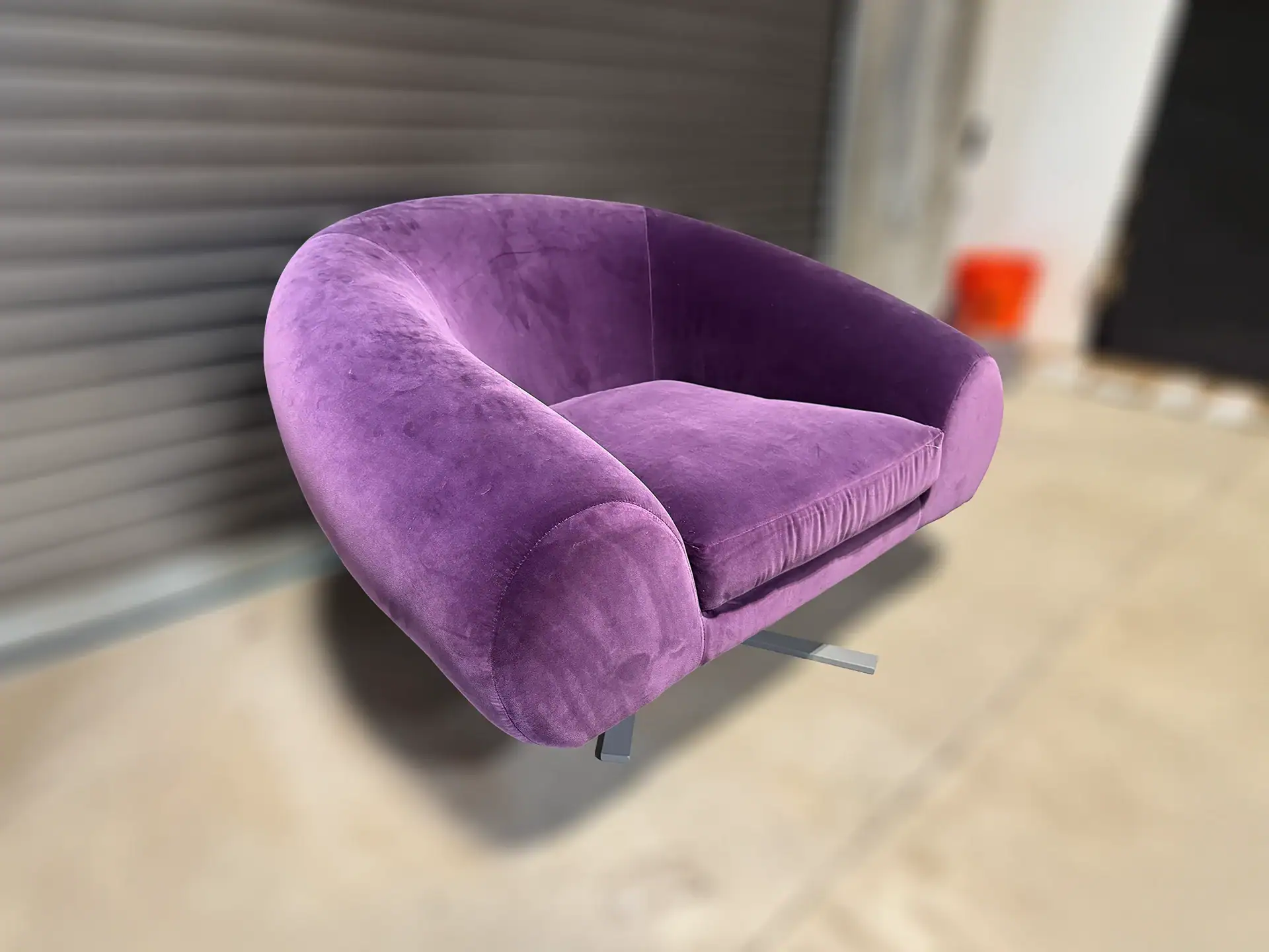Purple velvet lounge chair with modern design and curved shape.