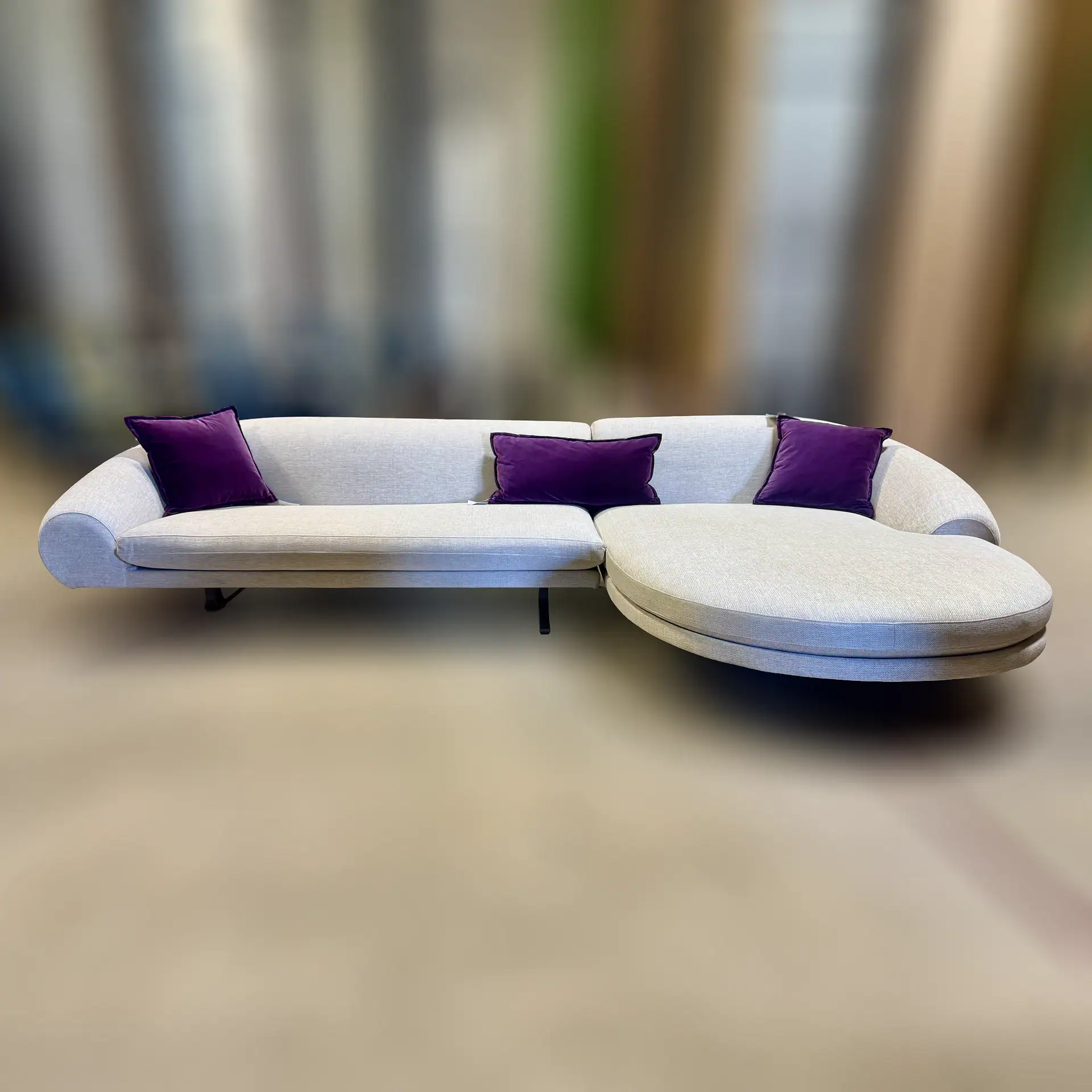 Modern white sofa with purple cushions in stylish living room setting.