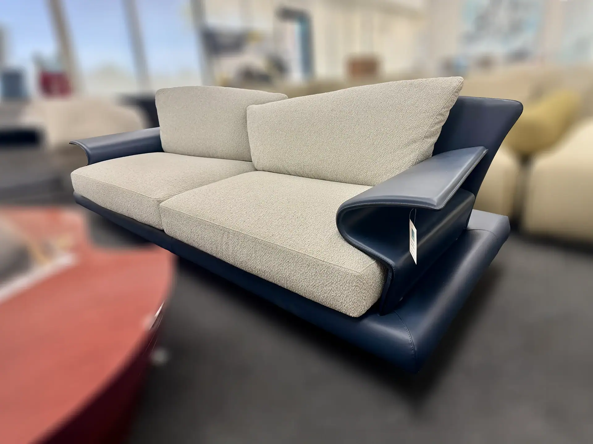 Contemporary sofa with beige cushions and black leather armrests.
