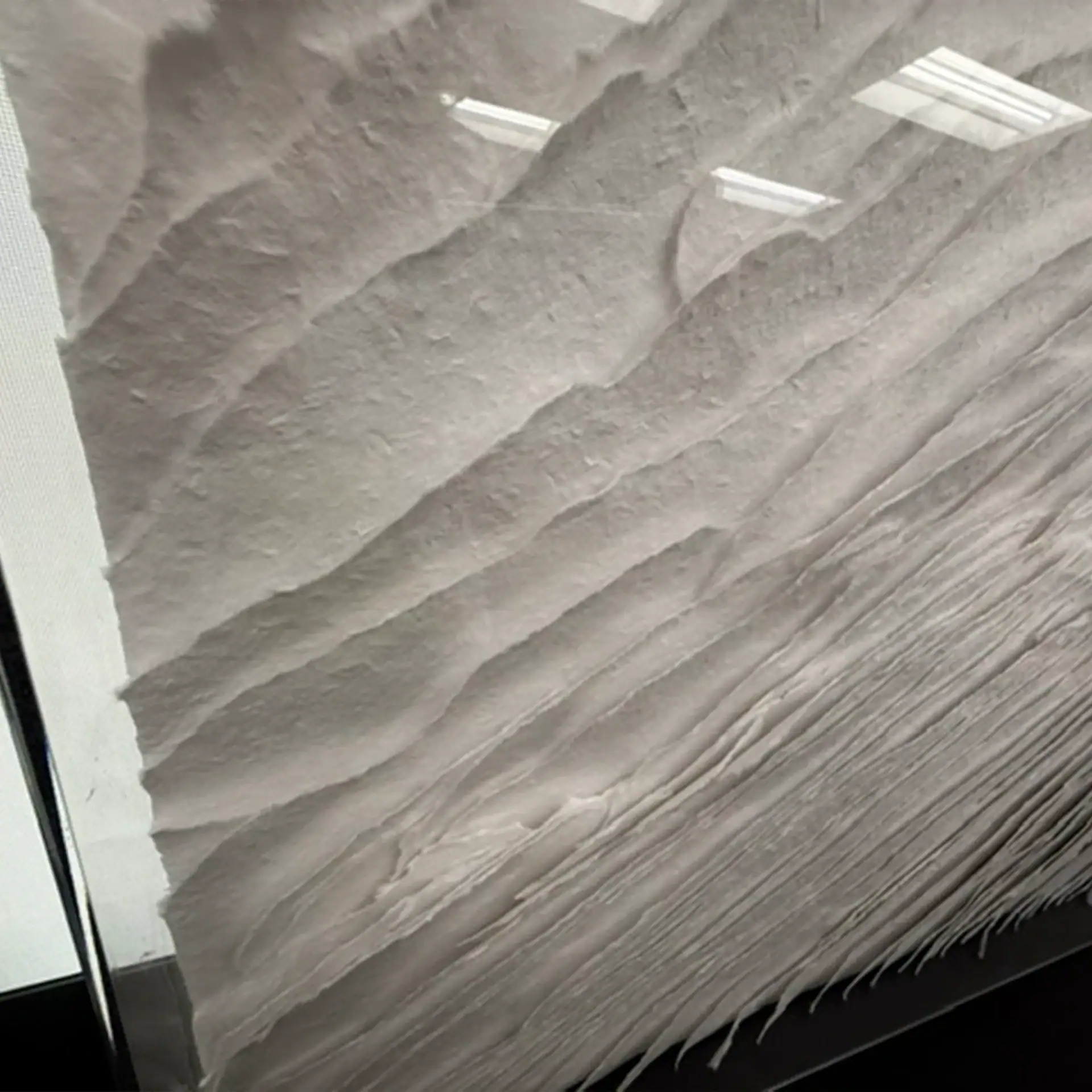 Textured wall art piece with layered, flowing design in neutral tones.