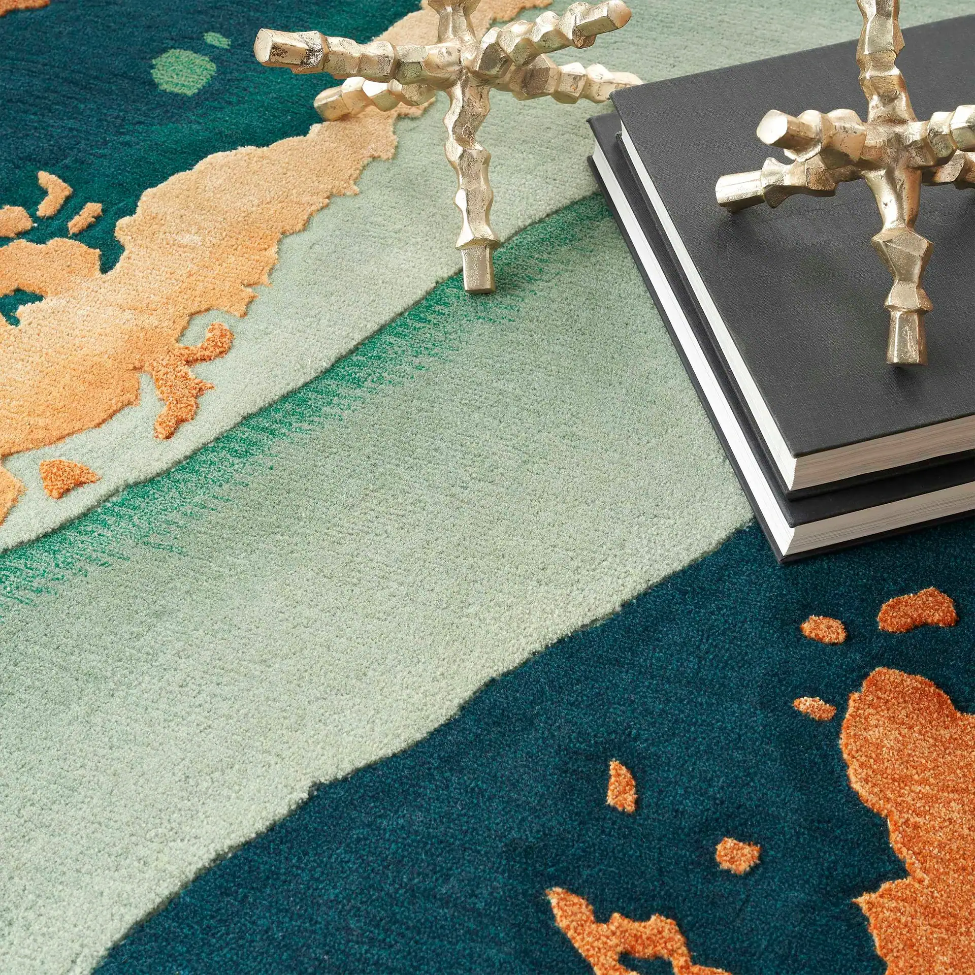 Colorful modern rug with decorative metallic sculptures and books.