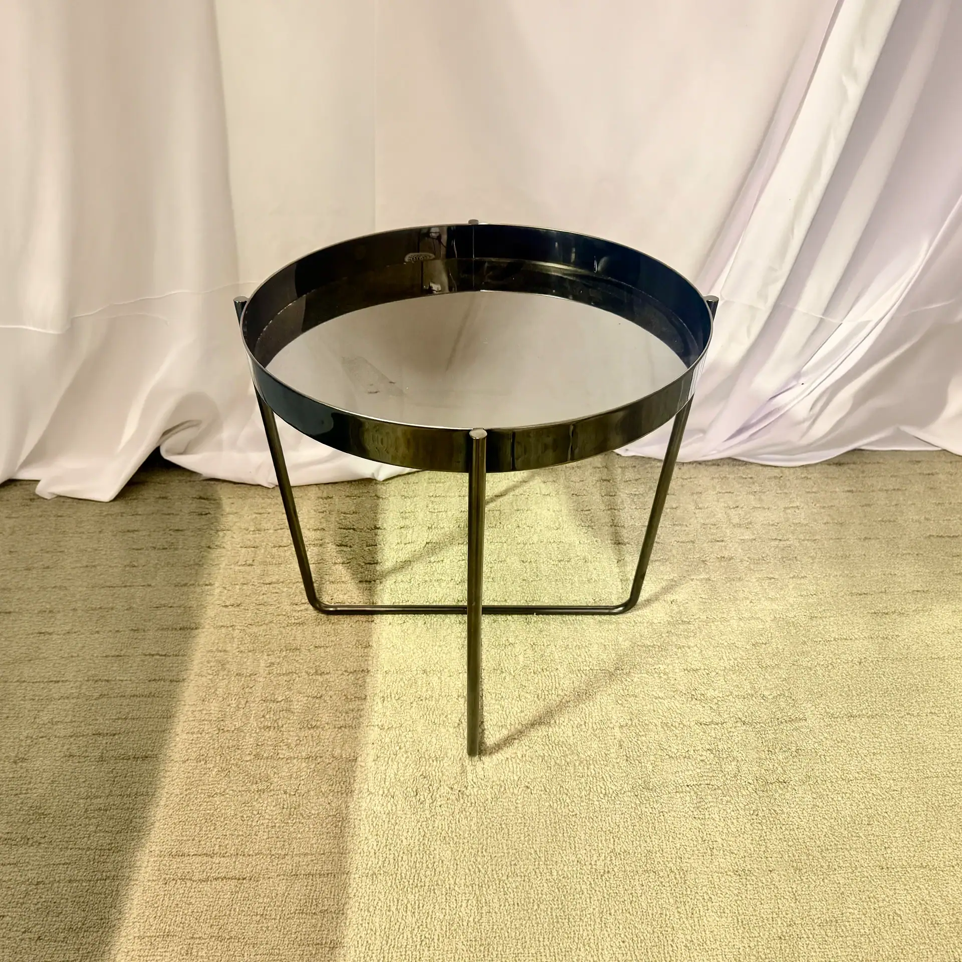 Modern black metal side table with circular top and minimalist design.