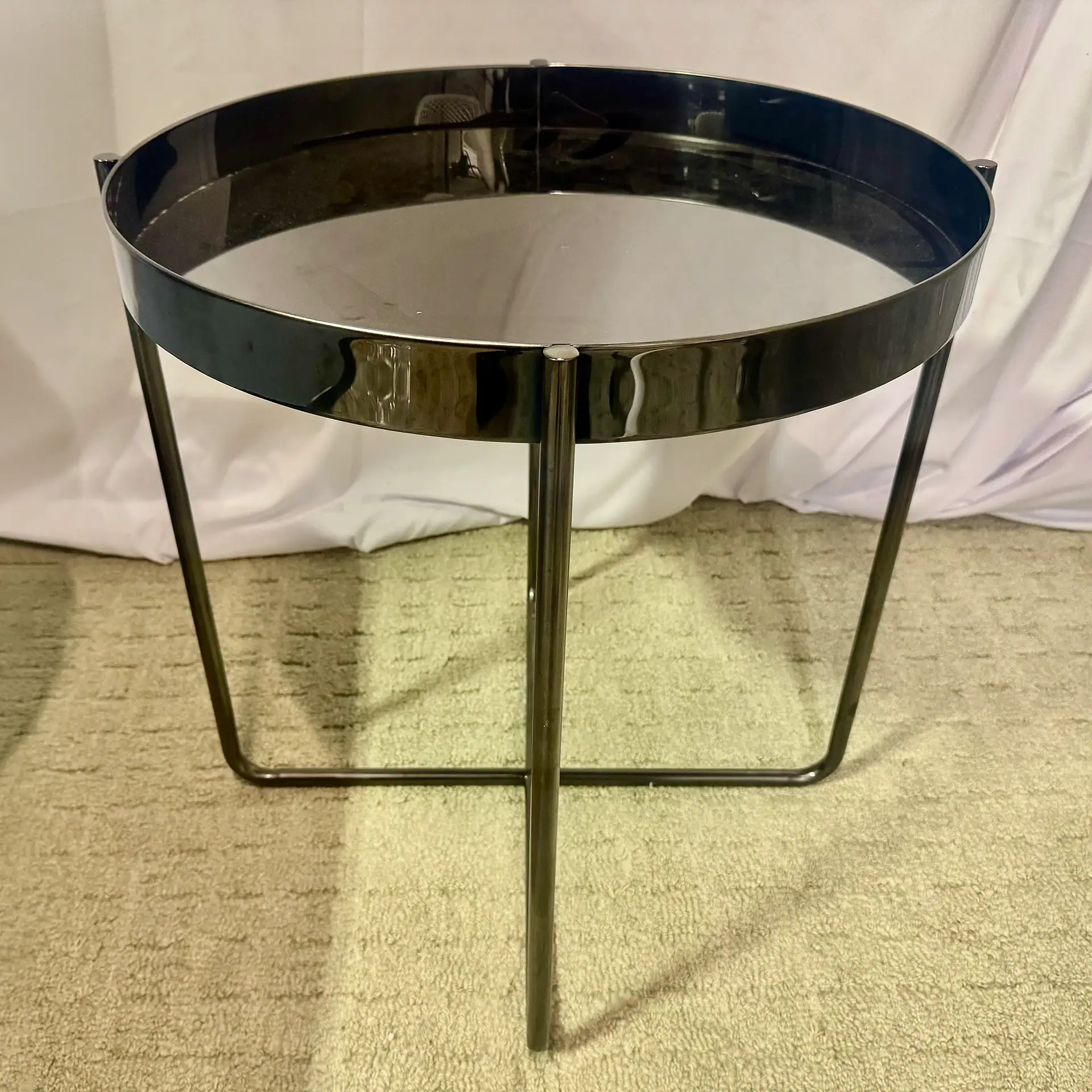 Modern black and chrome side table with circular top and minimalist design.
