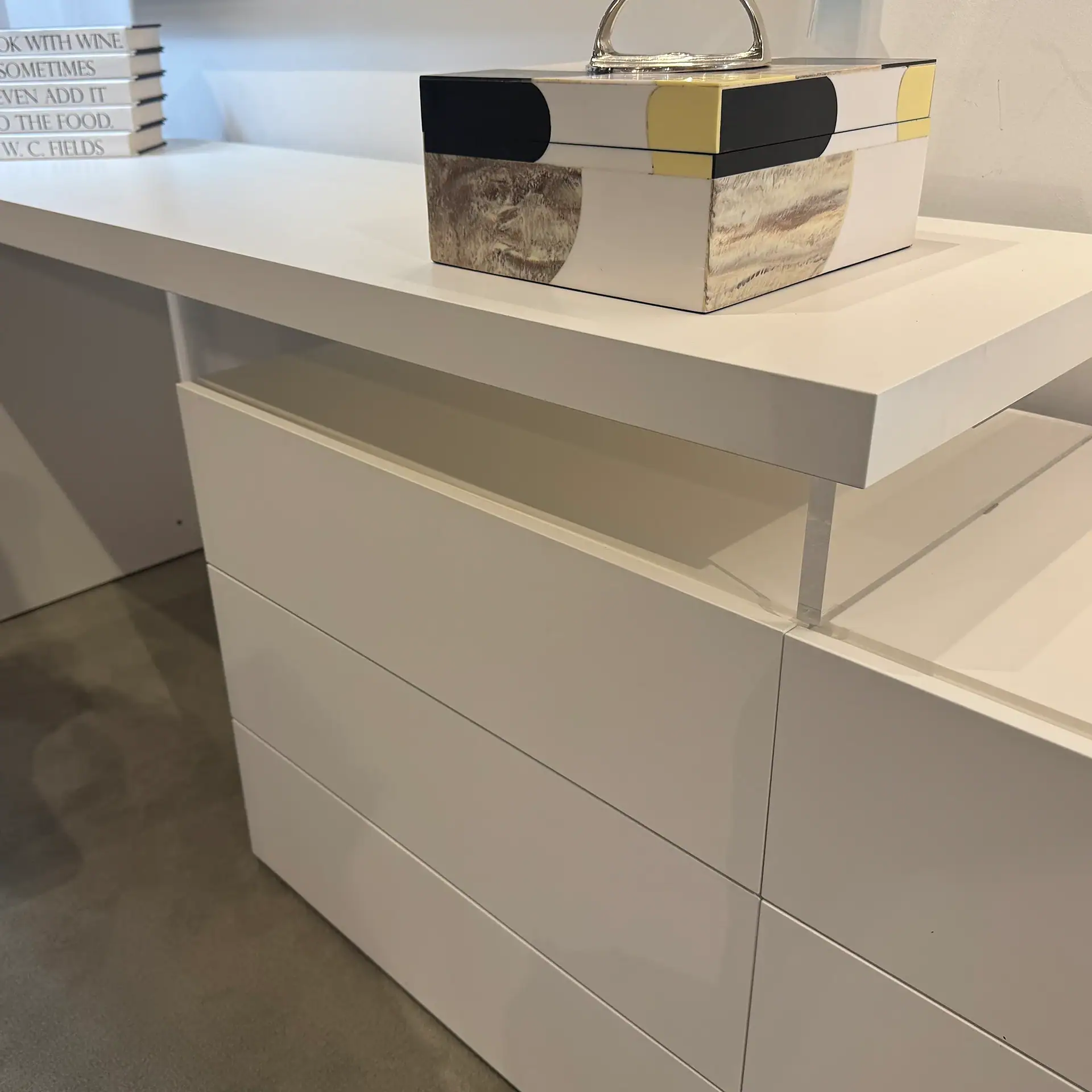 Contemporary white desk with drawers and decorative box on top.
