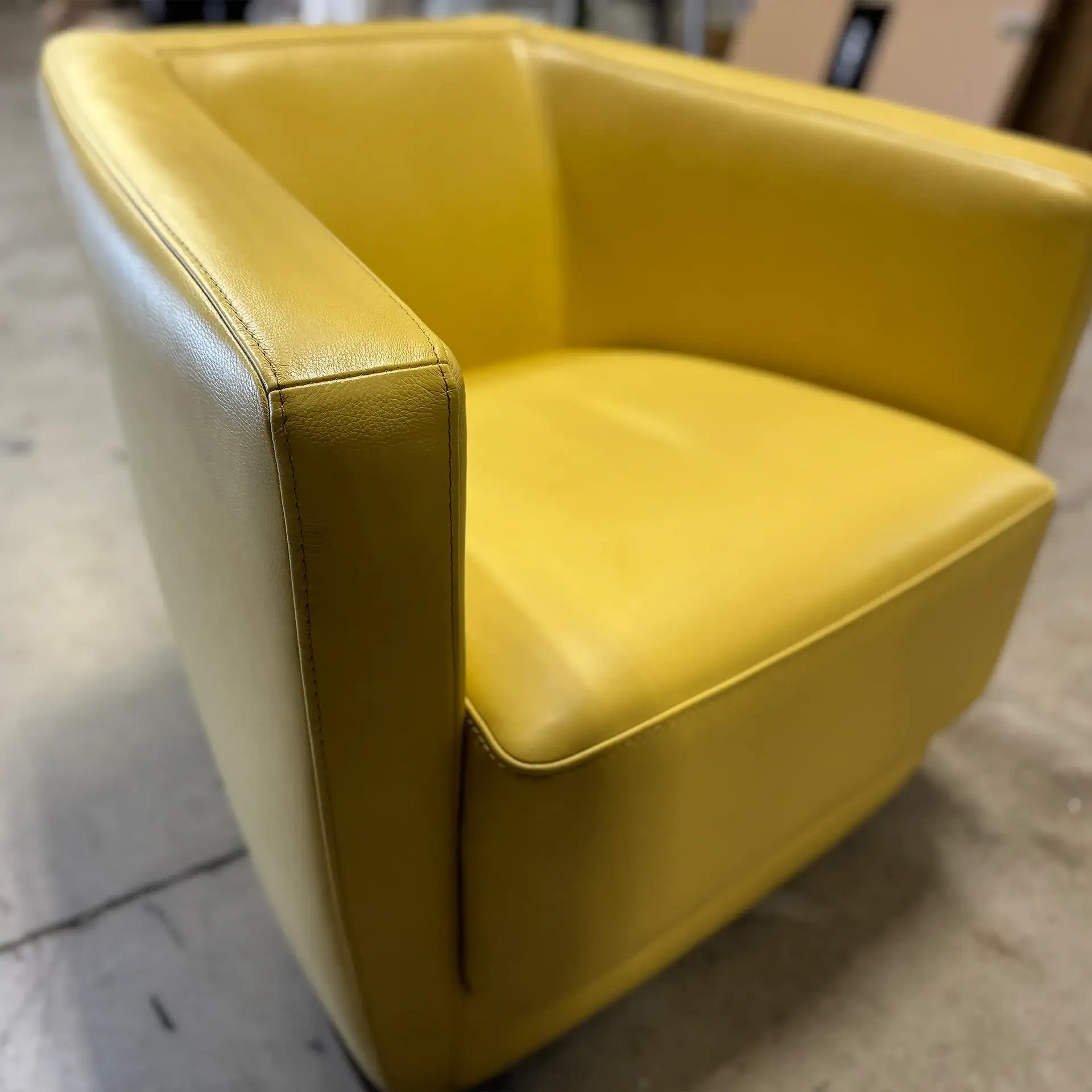 Bright yellow modern armchair with sleek design and smooth leather upholstery.