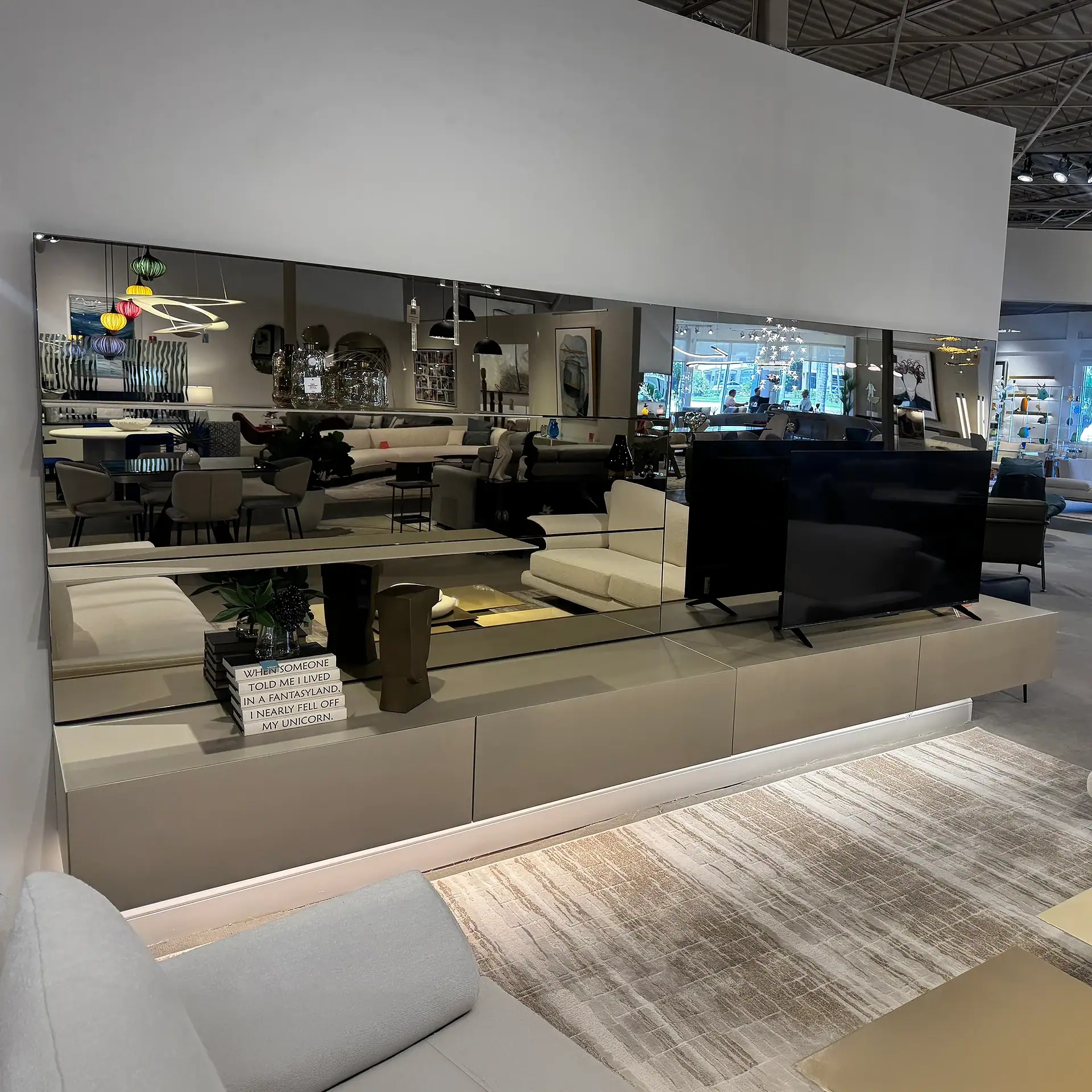 Contemporary wall unit with mirrored panels and TV setup at Sklar Furnishings.